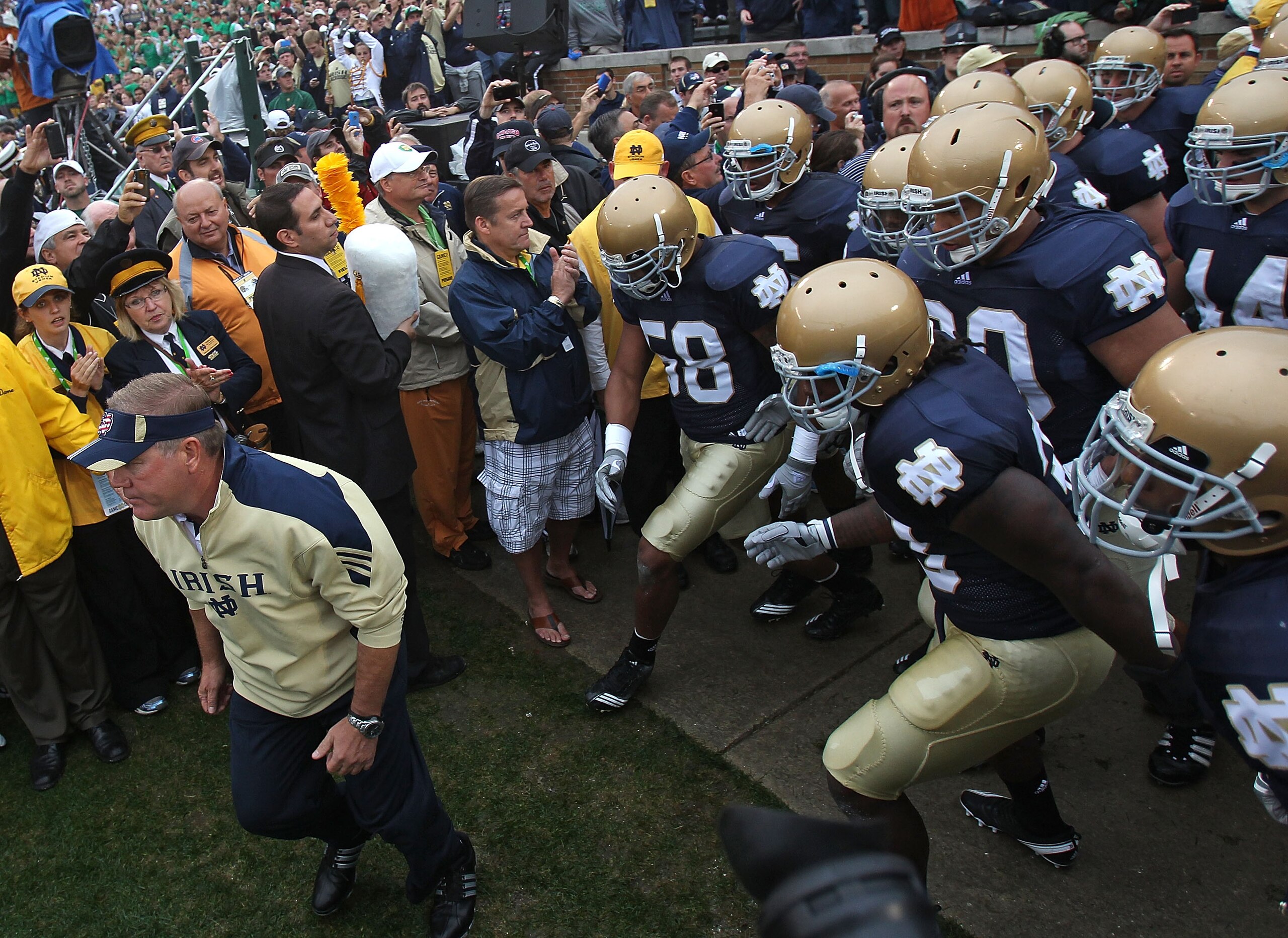 SOUTH BEND, IN - SEPTEMBER 11: Head coach Brian Kelly of the Notre Dame Fighting Irish (L) leads his team onto the field before a game against the Michigan Wolverines at Notre Dame Stadium on September 11, 2010 in South Bend, Indiana. Michigan defeated No