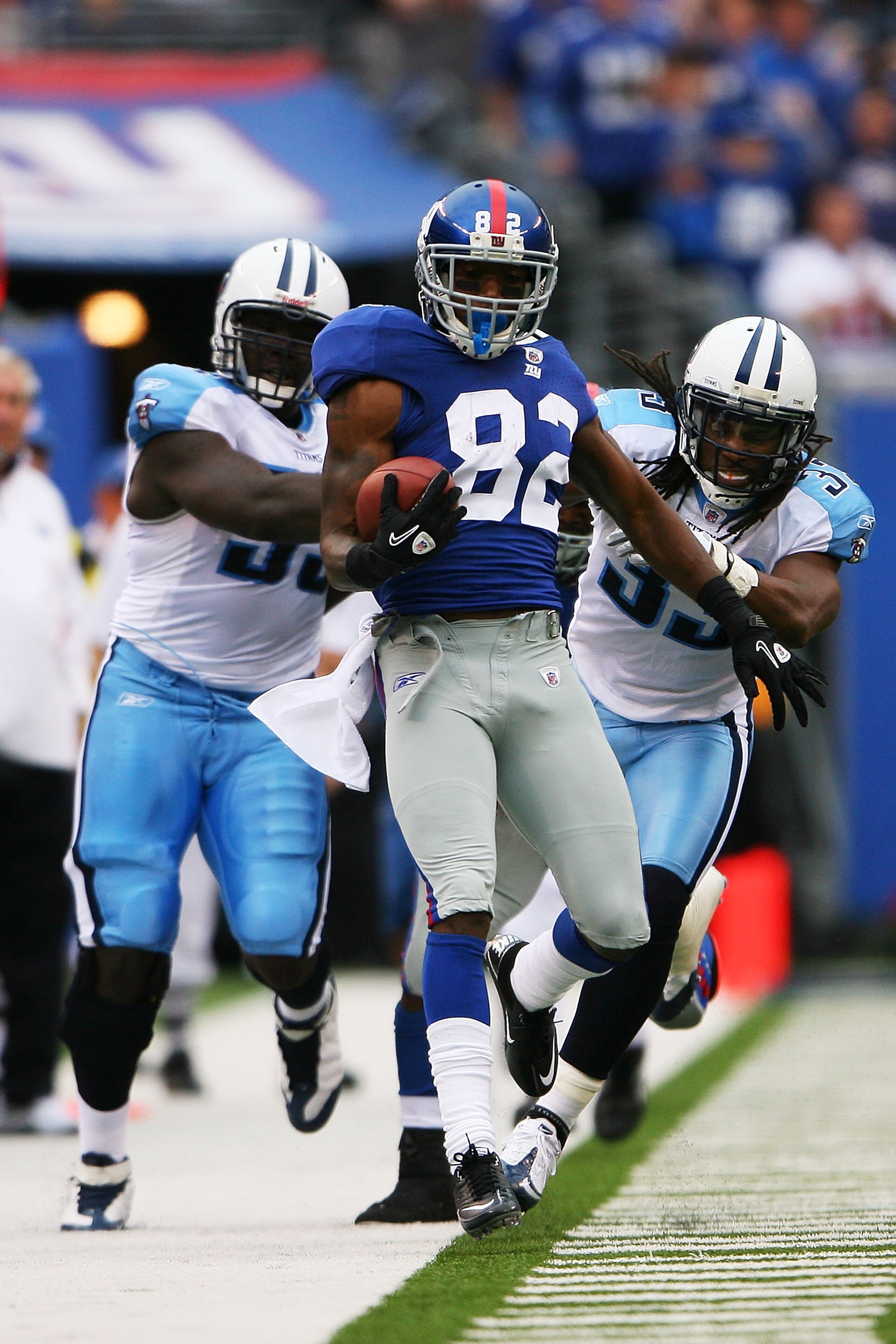 EAST RUTHERFORD, NJ - SEPTEMBER 26: Mario Manningham #82 of the New York Giants attempts to stay inbounds while William Hayes #95 (back left) and Michael Griffin (back right) #33 of the Tennessee Titans pull him out after a 25 yard reception at New Meadow