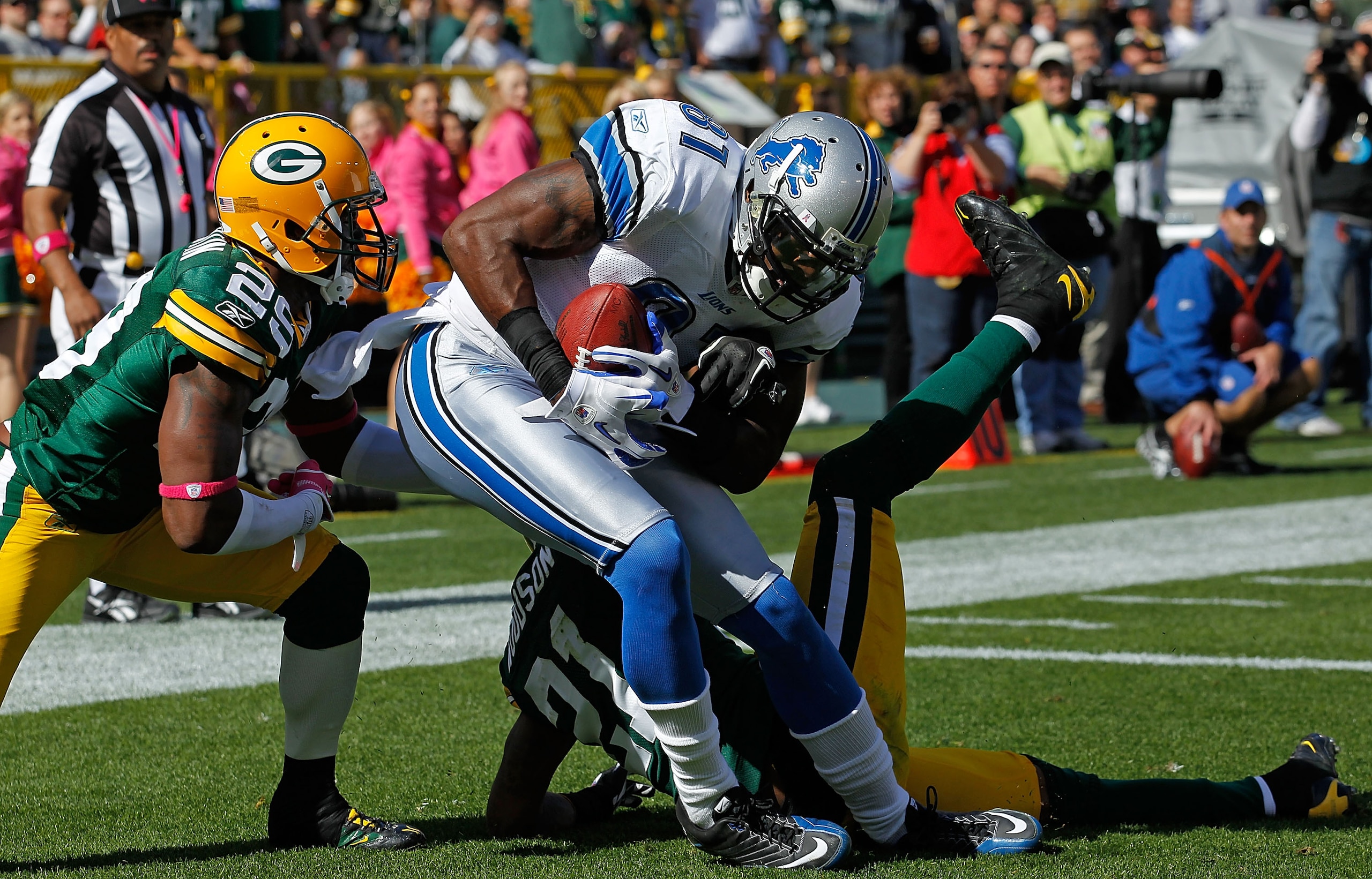 GREEN BAY, WI - OCTOBER 03: Calvin Johnson #81 of the Detroit Lions drops to the end zone after catching a touchdown pass between Derrick Martin #29 and Charles Woodson #21 of the Green Bay Packers at Lambeau Field on October 3, 2010 in Green Bay, Wiscons