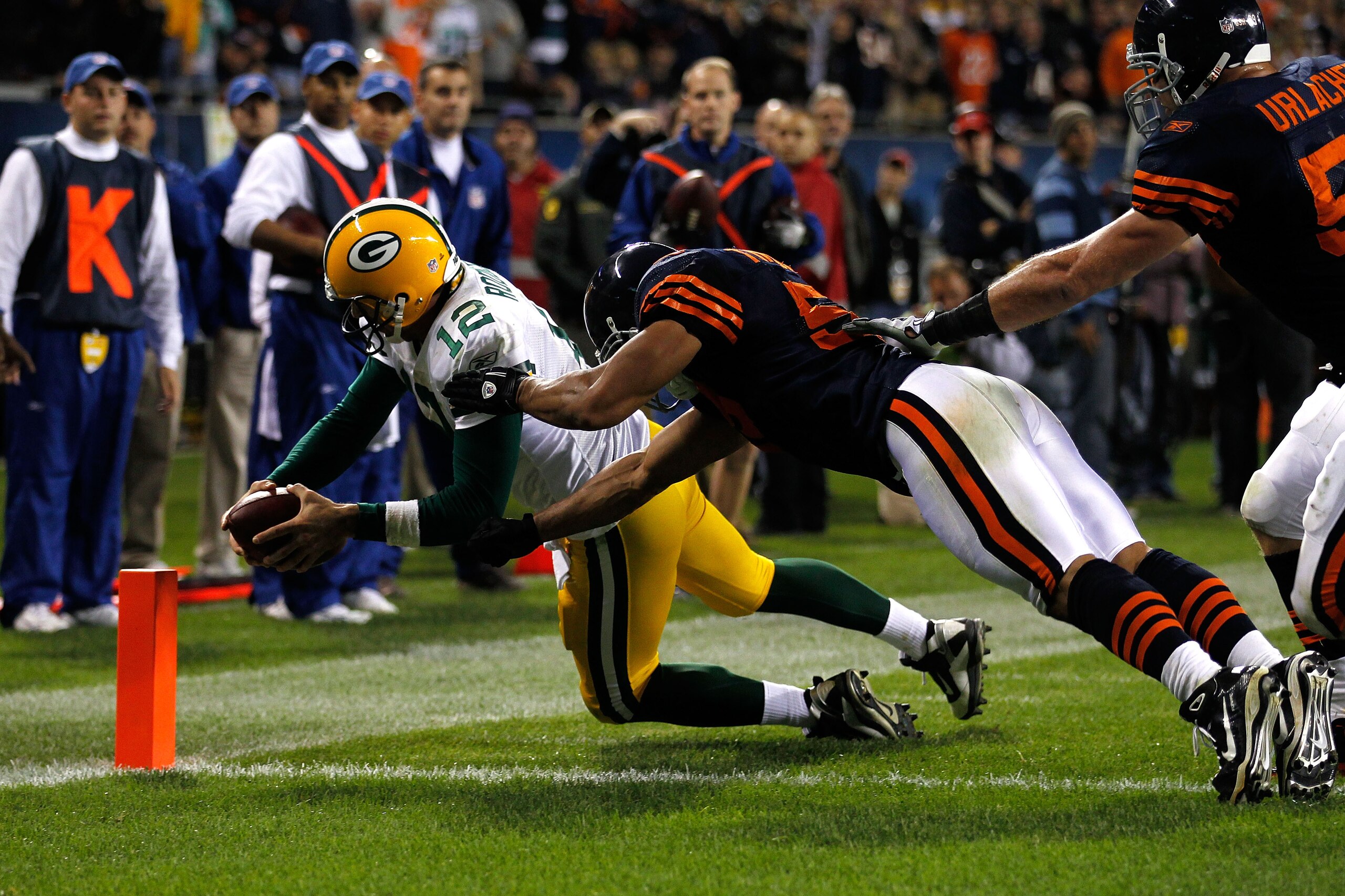 CHICAGO - SEPTEMBER 27:  Aaron Rodgers #12 of the Green Bay Packers dives into the endzone for a 3-yard rushing touchdown in the fourth quarter against Pisa Tinoisamoa #59 and Brian Urlacher #54 of the Chicago Bears at Soldier Field on September 27, 2010