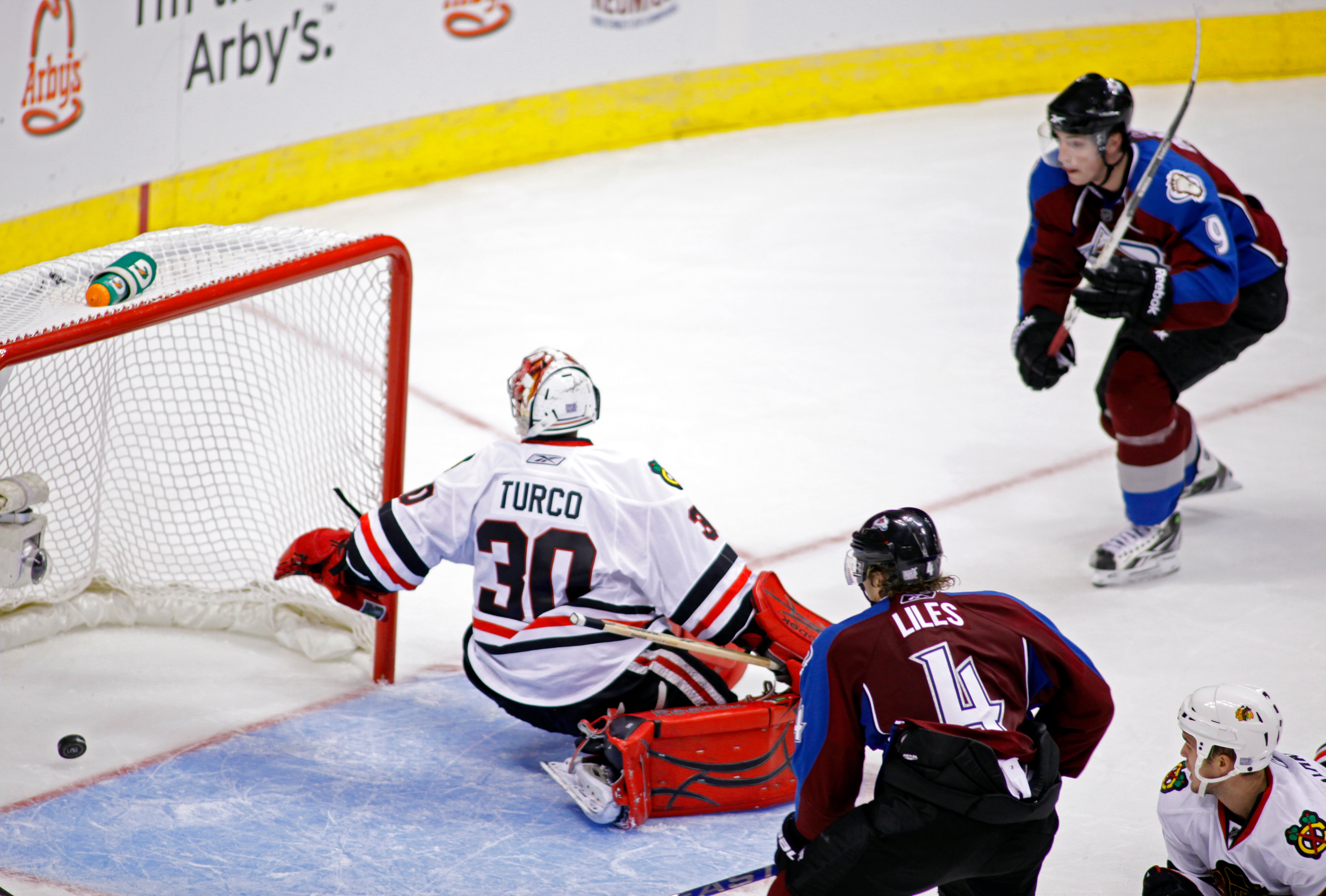 DENVER, CO - OCTOBER 7: John-Michael Liles #4 and Matt Duchene #9 of the Colorado Avalanche close in on Marty Turco #30 of the Chicago Blackhawks as a shot by Paul Stastny (not pictured) trickles past Turco in overtime during both team's season openers at
