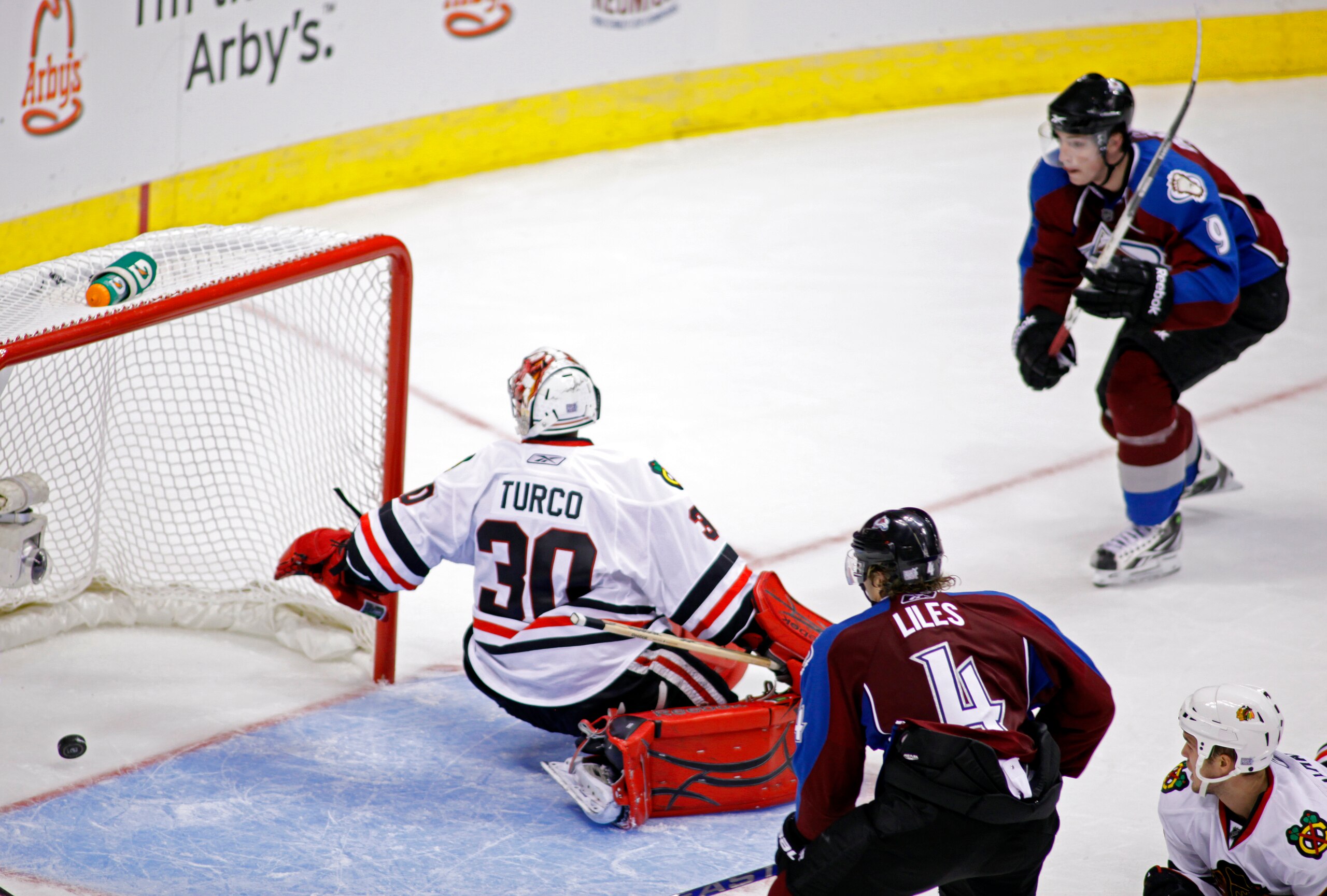 DENVER, CO - OCTOBER 7: John-Michael Liles #4 and Matt Duchene #9 of the Colorado Avalanche close in on Marty Turco #30 of the Chicago Blackhawks as a shot by Paul Stastny (not pictured) trickles past Turco in overtime during both team's season openers at