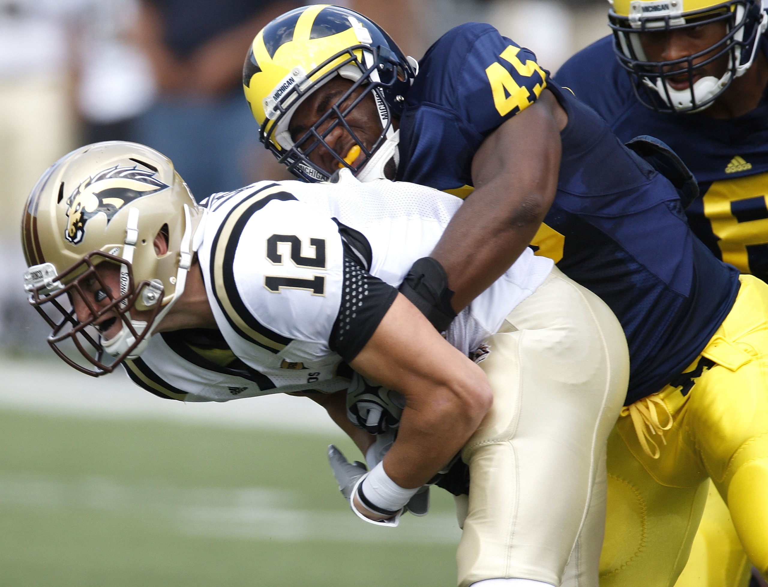 ANN ARBOR, MI - SEPTEMBER 5:  Obi Ezeh #45 of the Michigan Wolverines tackles Robert Arnheim #12 of the Western Michigan Broncos during the game on September 5, 2009 at Michigan Stadium in Ann Arbor, Michigan. (Photo by Gregory Shamus/Getty Images)