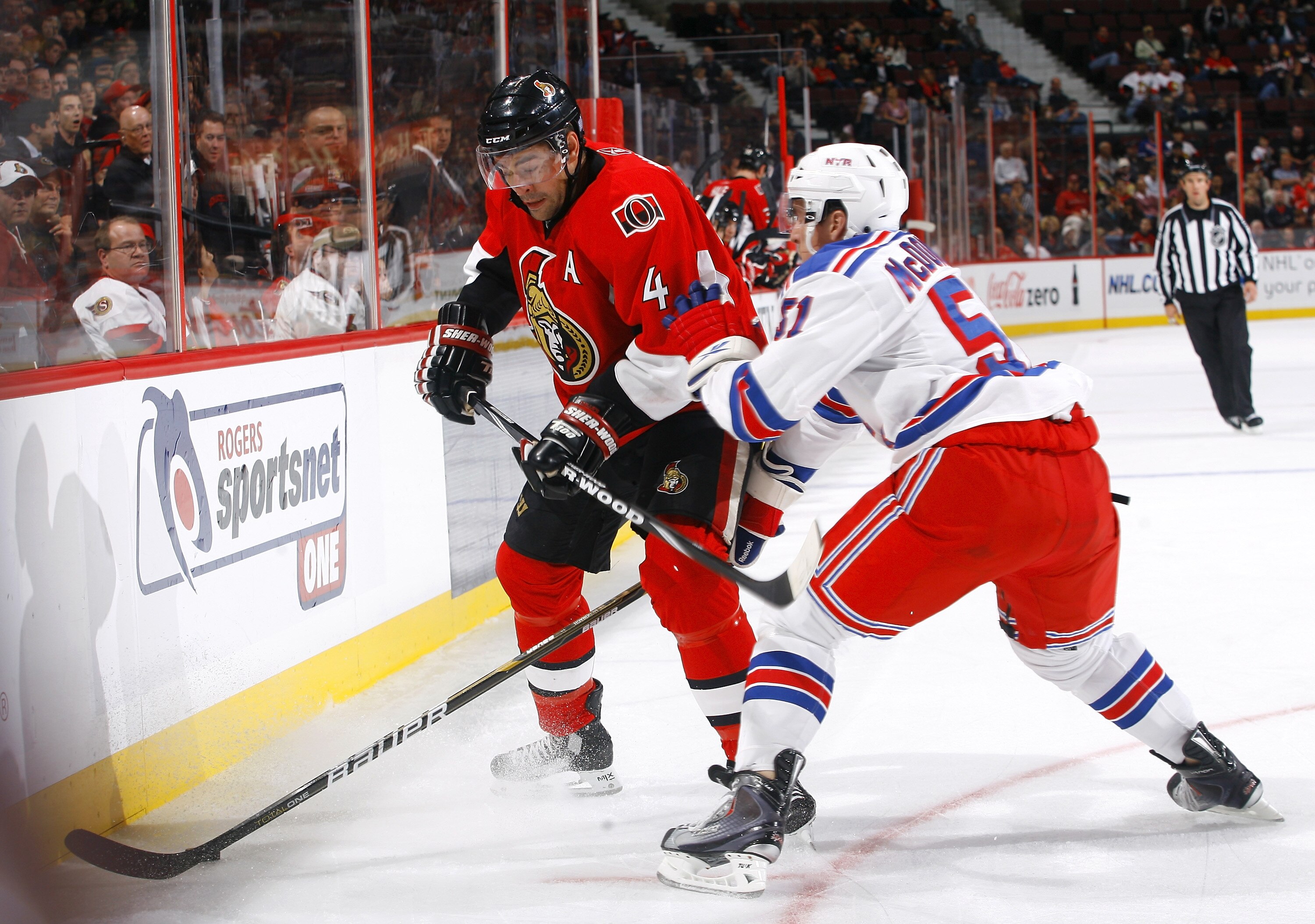 KANATA, ON - OCTOBER 02:  Chris Phillips #4 of the Ottawa Senators and Ryan McDonagh #51 of the New York Rangers battle for the puck along the near boards at Scotiabank Place on October 2, 2010 in Kanata, Ontario, Canada.  The Ottawa Senators defeated the