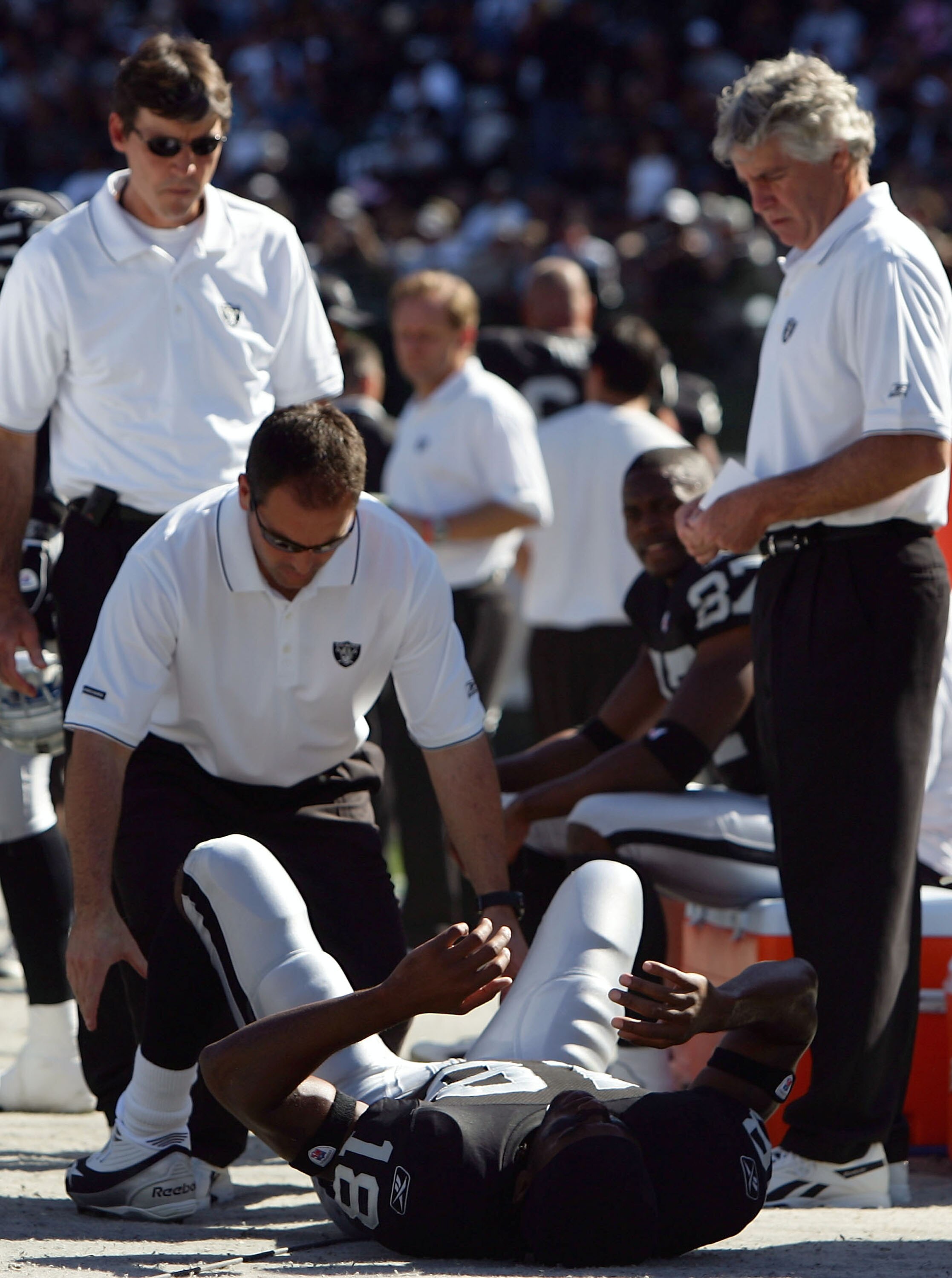 OAKLAND, CA - OCTOBER 16:  Wide receiver Randy Moss #18 of the Oakland Raiders is attended to on the sideline after sustaining an injury during the first quarter of the game against the San Diego Chargers at McAfee Coliseum on October 16, 2005 in Oakland,