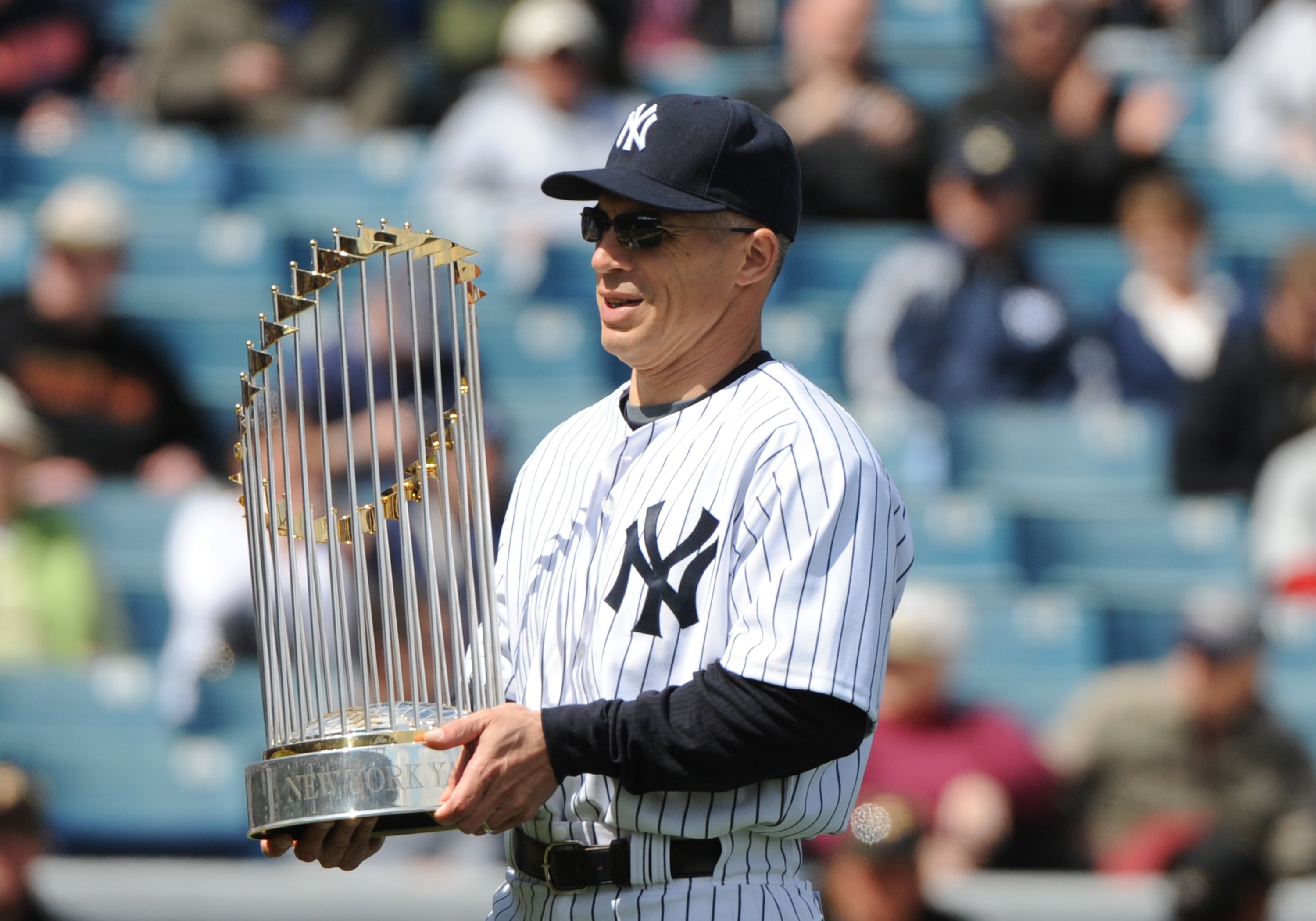 TAMPA, FL - MARCH 3: Manager Joe Girardi #28 of the New York Yankees carries the World Series trophy before play against the Pittsburgh Pirates on March 3, 2010 at the George M. Steinbrenner  Field in Tampa, Florida. (Photo by Al Messerschmidt/Getty Image