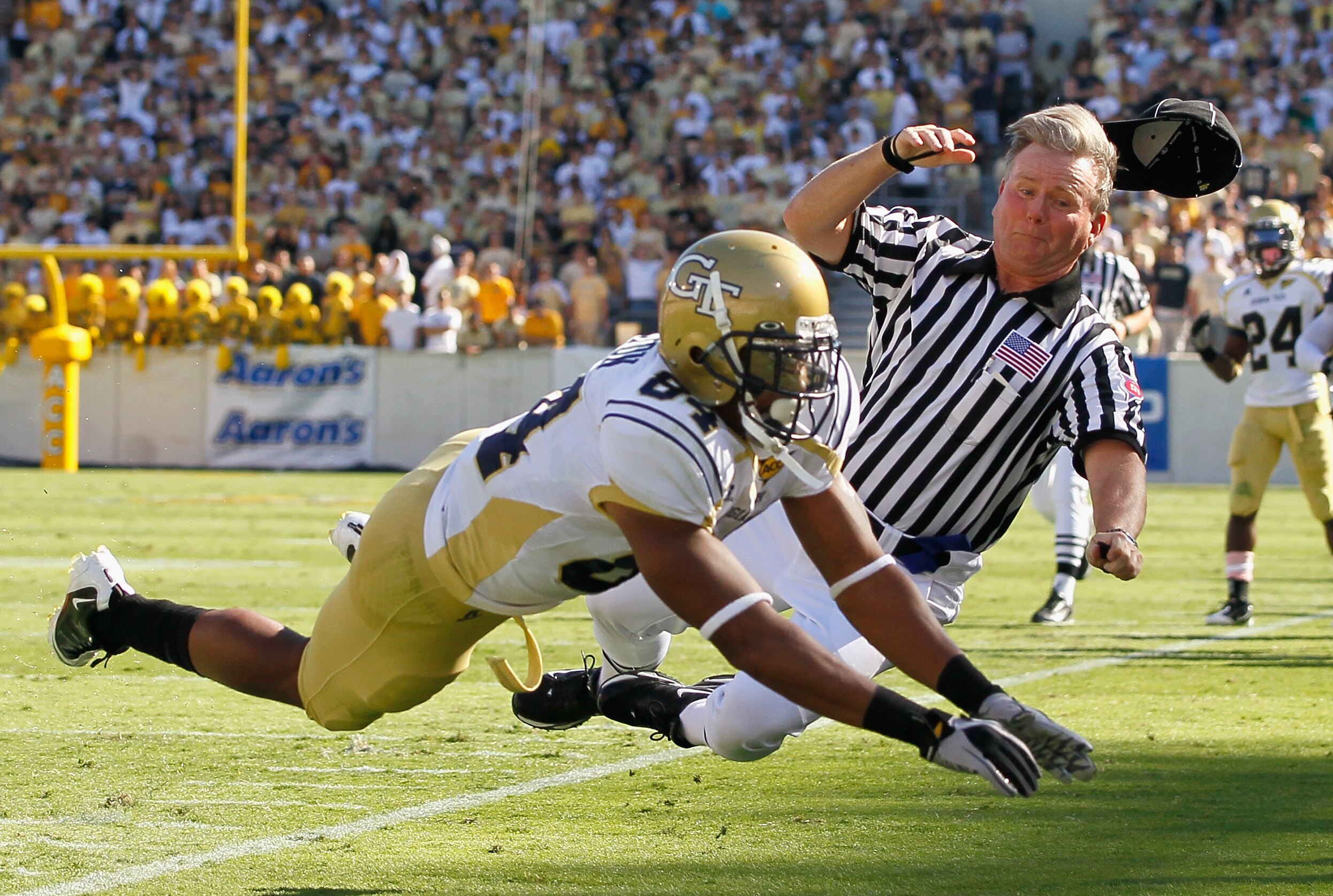 ATLANTA - OCTOBER 09:  Tyler Melton #84 of the Georgia Tech Yellow Jackets collides with field judge Billy Beckett (R) as he fails to pull in this reception against the Virginia Cavaliers at Bobby Dodd Stadium on October 9, 2010 in Atlanta, Georgia.  (Pho