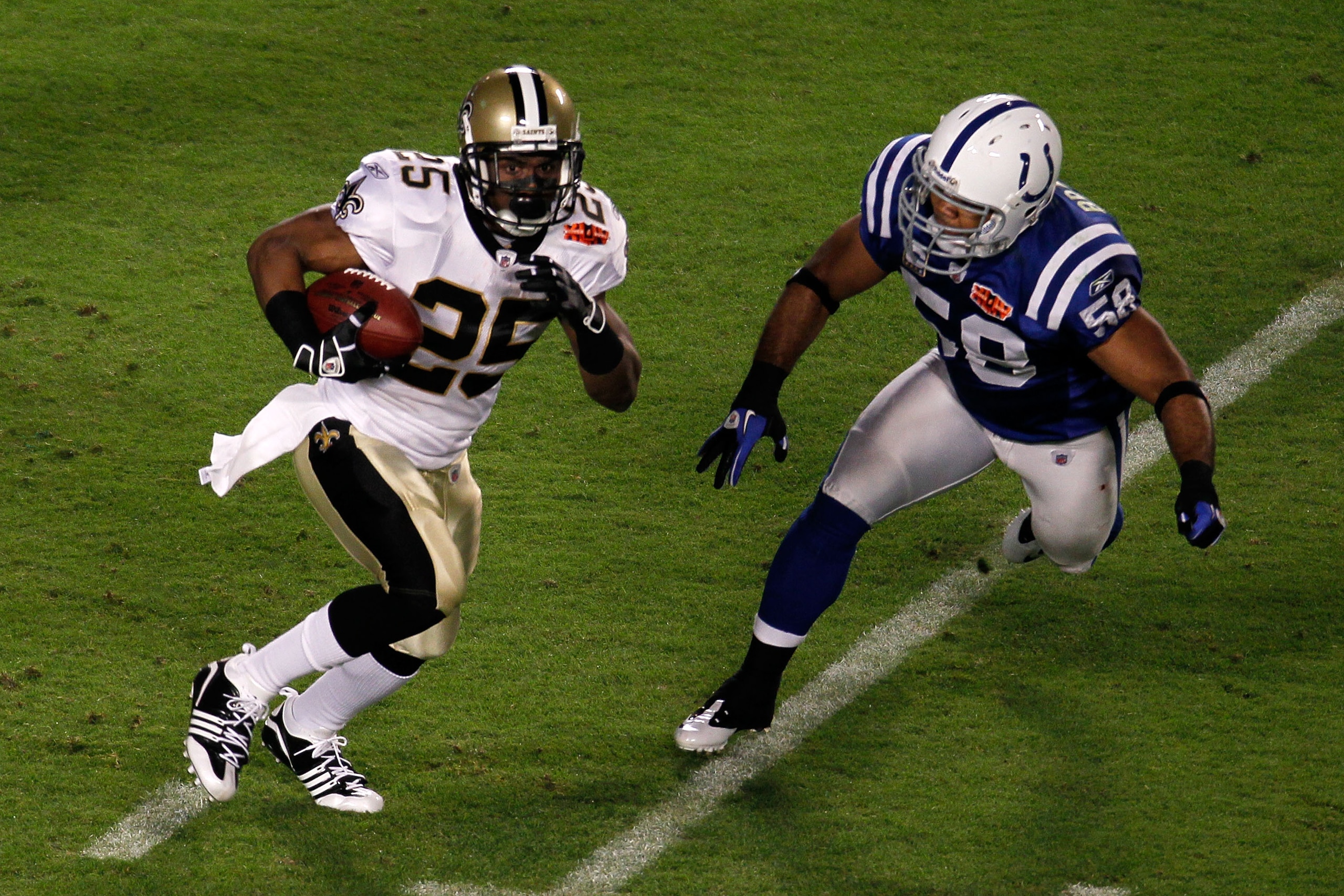 MIAMI GARDENS, FL - FEBRUARY 07:  Reggie Bush #25 of the New Orleans Saints runs with the ball  against Gary Brackett #58 of the Indianapolis Colts during Super Bowl XLIV on February 7, 2010 at Sun Life Stadium in Miami Gardens, Florida.  (Photo by Doug B
