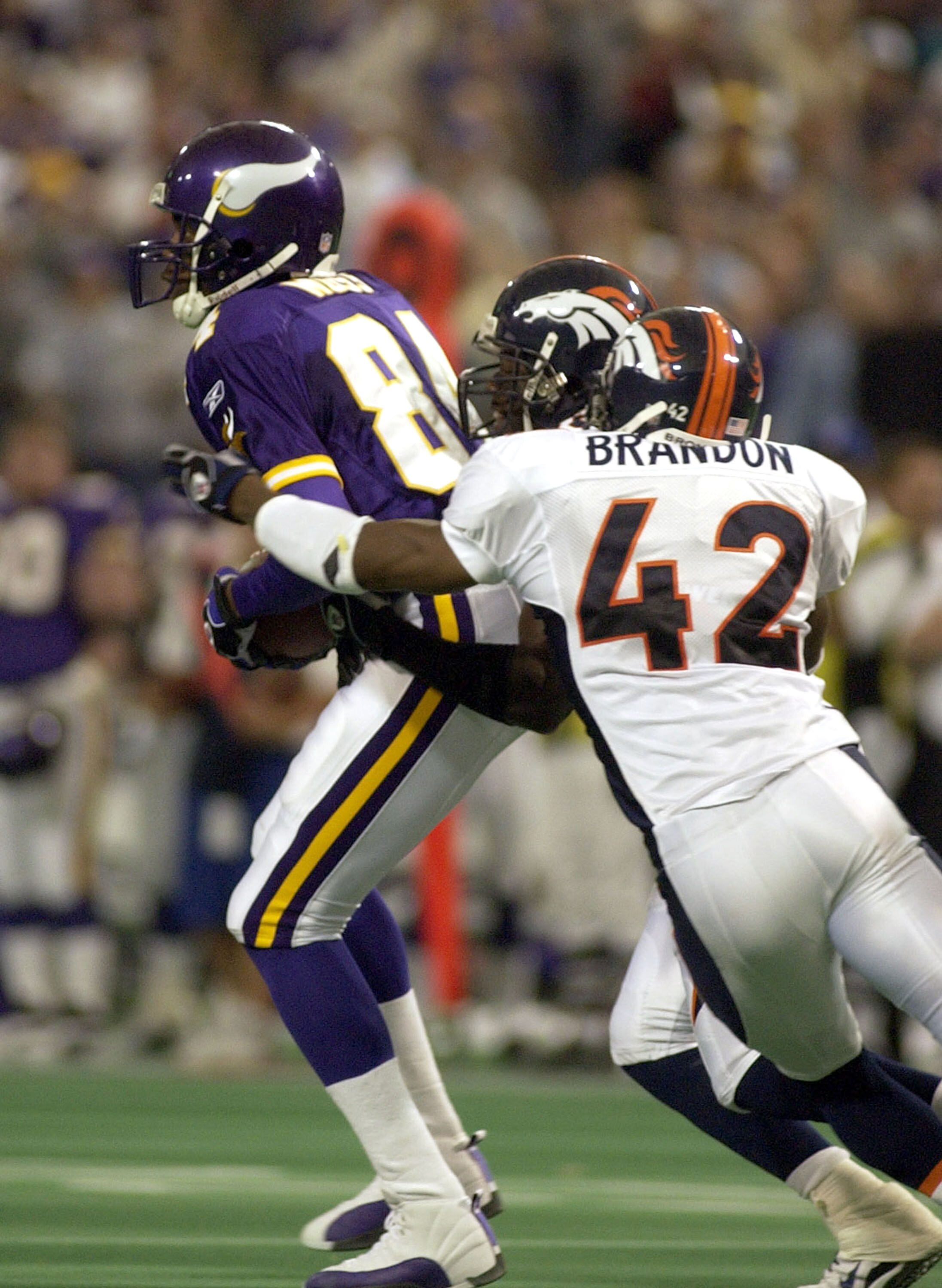 MINNEAPOLIS - OCTOBER 19:  Wide reciever Randy Moss #84 of the Minnesota Vikings catches a Daunte Culpepper pass then latterals the pass for a touchdown before he is tackled by saftey Sam Brandon #42 and saftey Nick Ferguson #25 of the Denver Broncos Octo