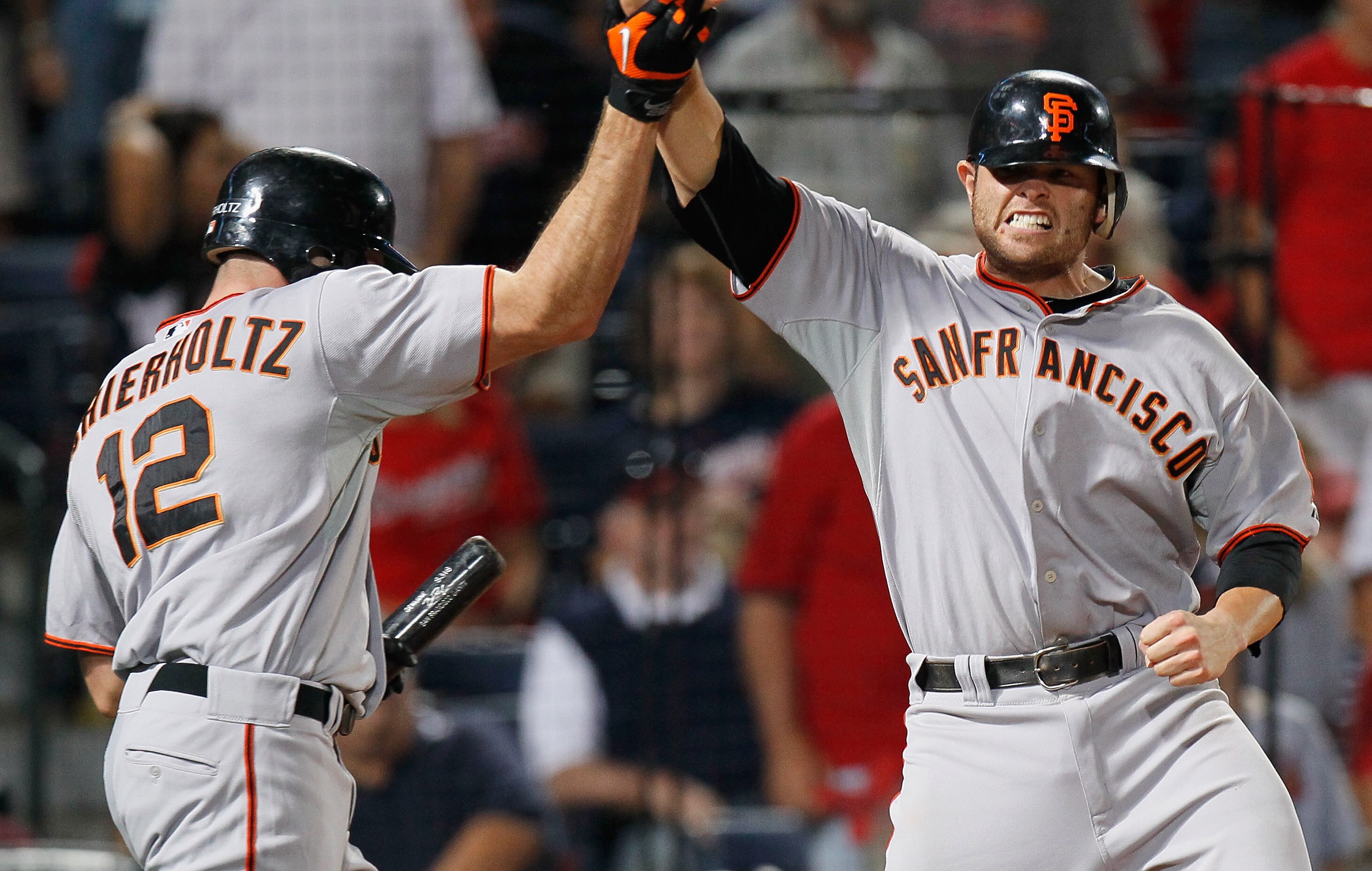 ATLANTA - OCTOBER 10:  Freddy Sanchez #21 of the San Francisco Giants celebrates with Nate Schierholtz #12 after scoring the go-ahead run off an error by Brooks Conrad #26 of the Atlanta Braves in the ninth inning during Game Three of the NLDS of the 2010