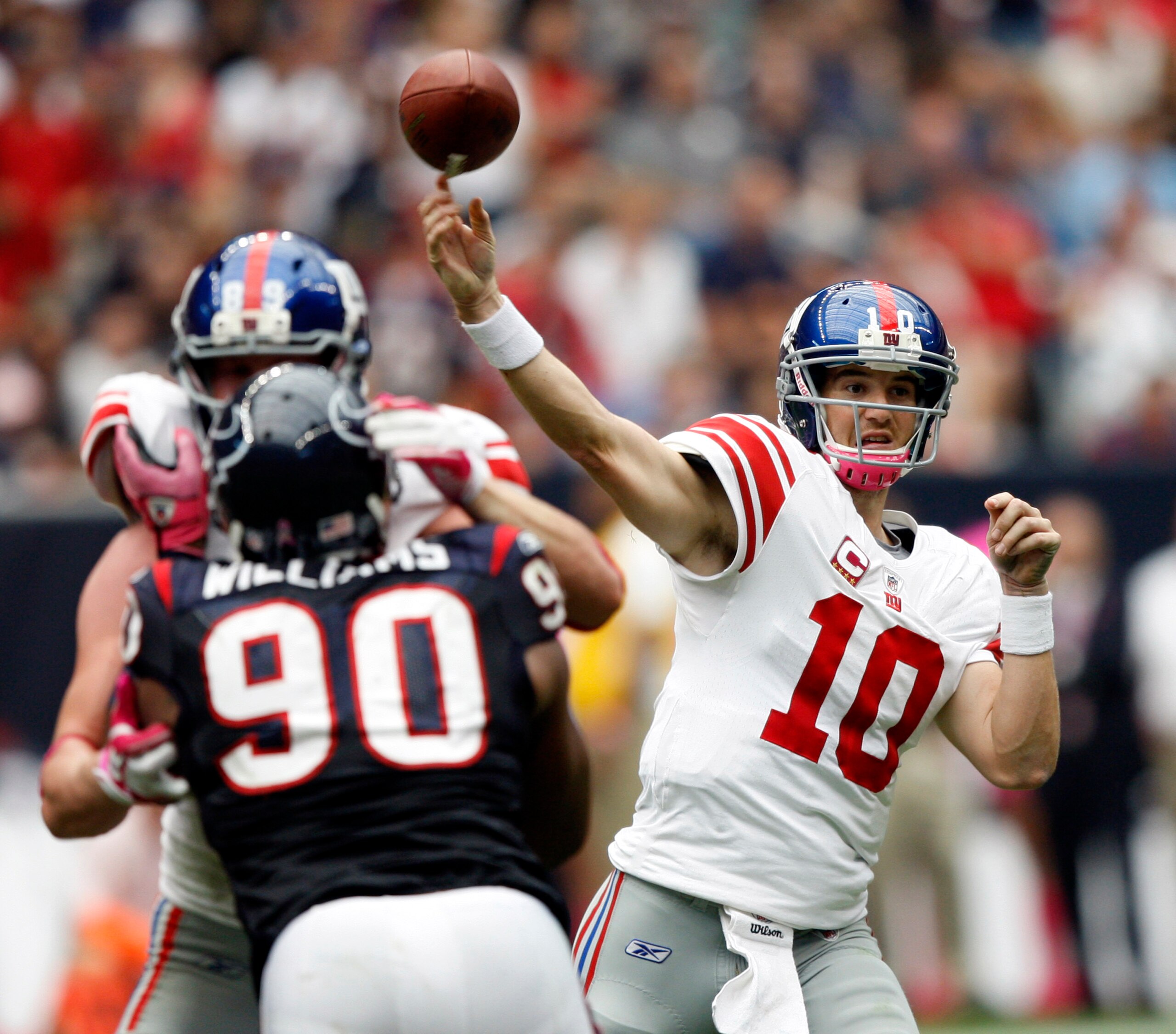 HOUSTON - OCTOBER 10:  Quarterback Eli Manning #10 of the New York Giants throws downfield before defensive end Mario Williams #90 can get to him at Reliant Stadium on October 10, 2010 in Houston, Texas. New York won 34-10.  (Photo by Bob Levey/Getty Imag