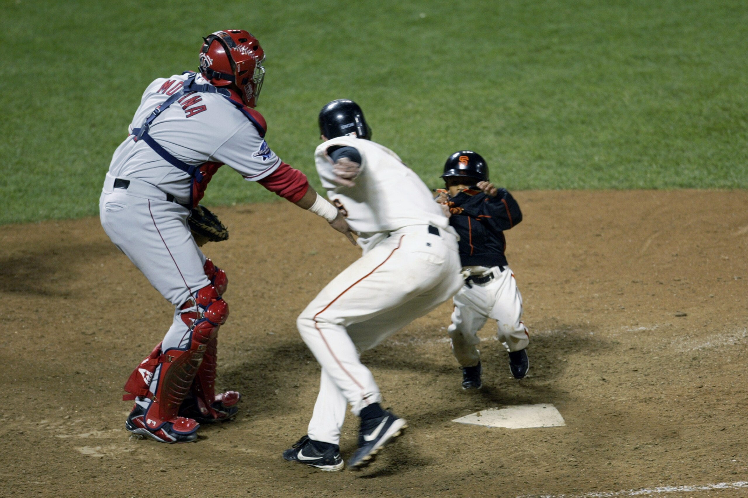 SAN FRANCISCO - OCTOBER 23:  Bengie Molina #1 of the Anaheim Angels and J.T. Snow #6 of the San Francisco Giants try to get bat boy Darren Baker out of harms way as he runs on the field during play in game four of the World Series on October 23, 2002 at P