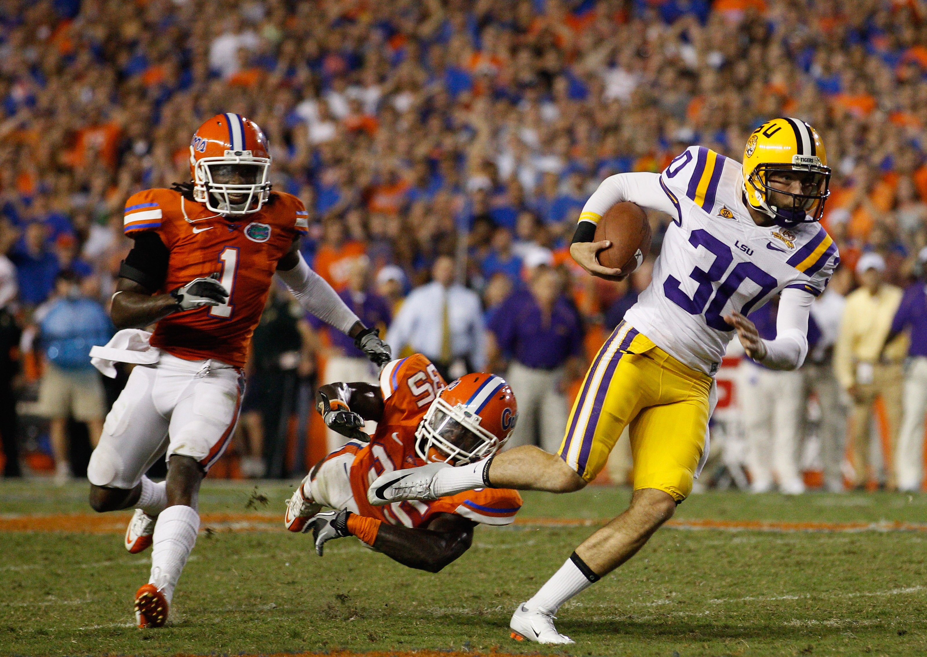 GAINESVILLE, FL - OCTOBER 09:  Punter Josh Jasper #30 of the Louisiana State Tigers runs a fake punt for yardage past Ahmad Black #35 and Janoris Jenkins #1 of the Florida Gators during the game at Ben Hill Griffin Stadium on October 9, 2010 in Gainesvill