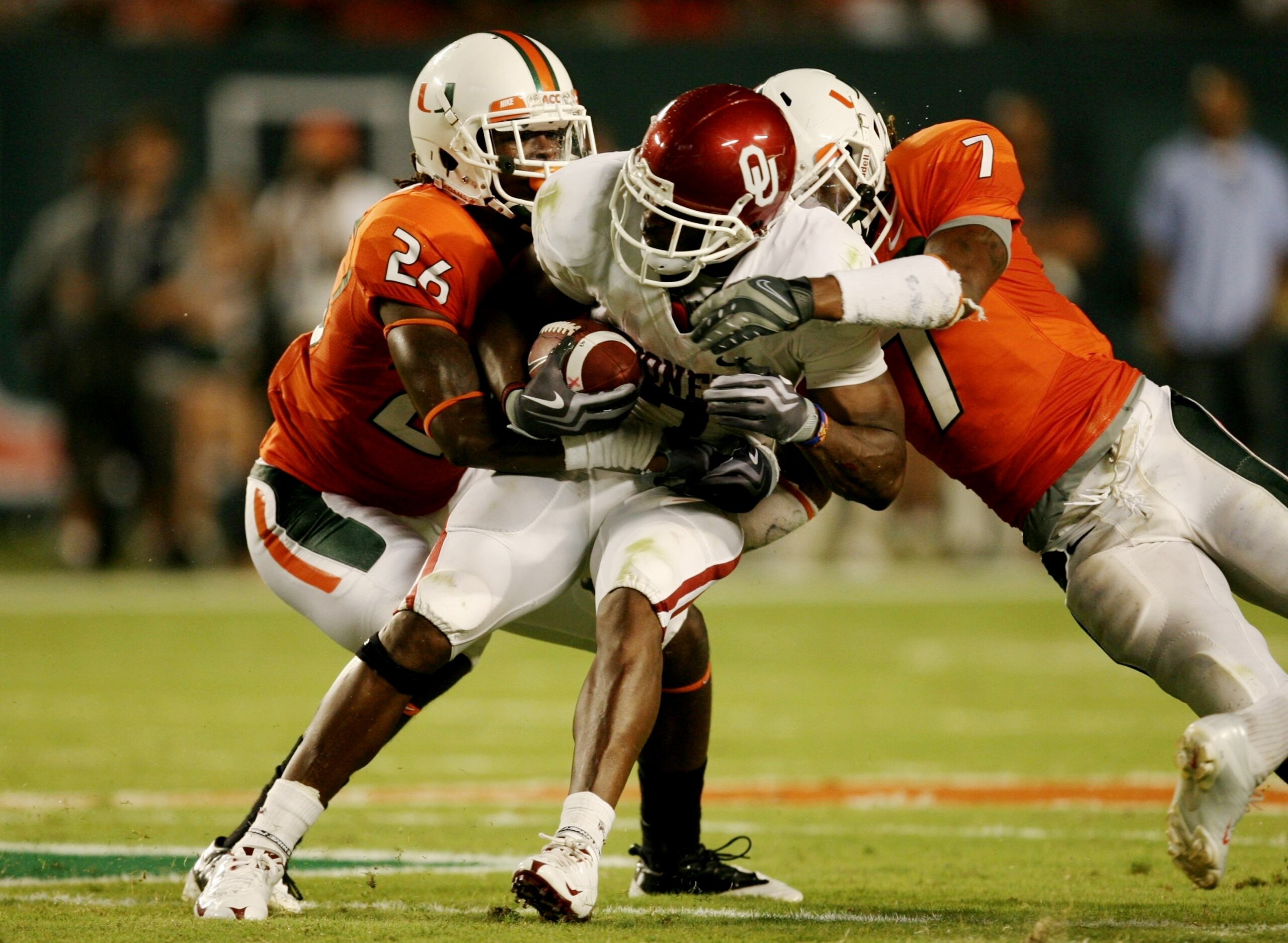 MIAMI GARDENS, FL - OCTOBER 3:  DeMarco Murray #7 of the Oklahoma Sooners gets tackled by Ray Ray Armstrong #26 and Vaughn Telemaque #7  of the Miami Hurricanes after getting first down in the second quarter of the game on October 3, 2009 at Landshark Sta
