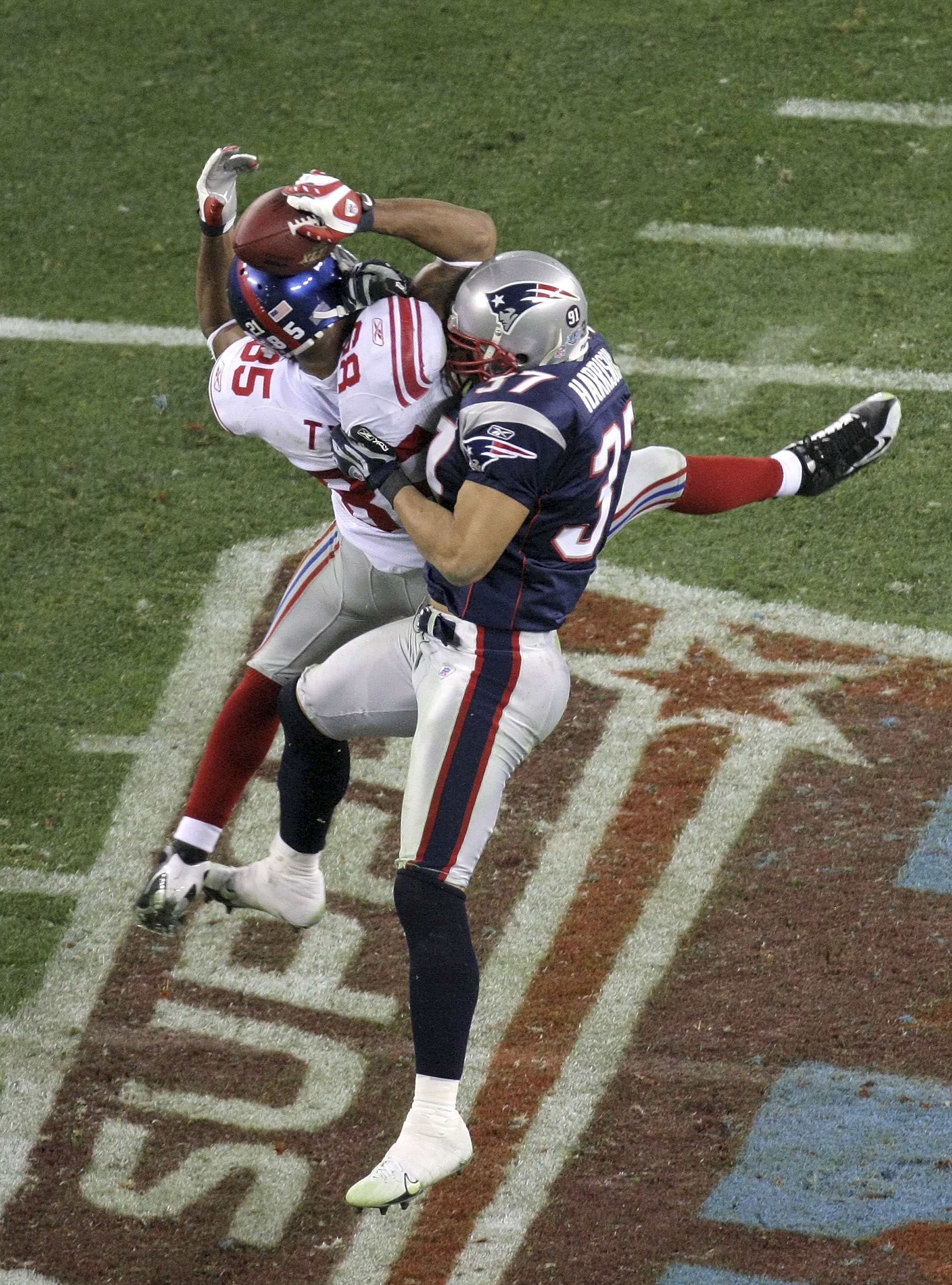 GLENDALE, AZ - FEBRUARY 03:  David Tyree #85 of the New York Giants catches a 32-yard pass from Eli Manning #10 as Rodney Harrison #37 of the New England Patriots attempts to knock it out in the fourth quarter of Super Bowl XLII on February 3, 2008 at the