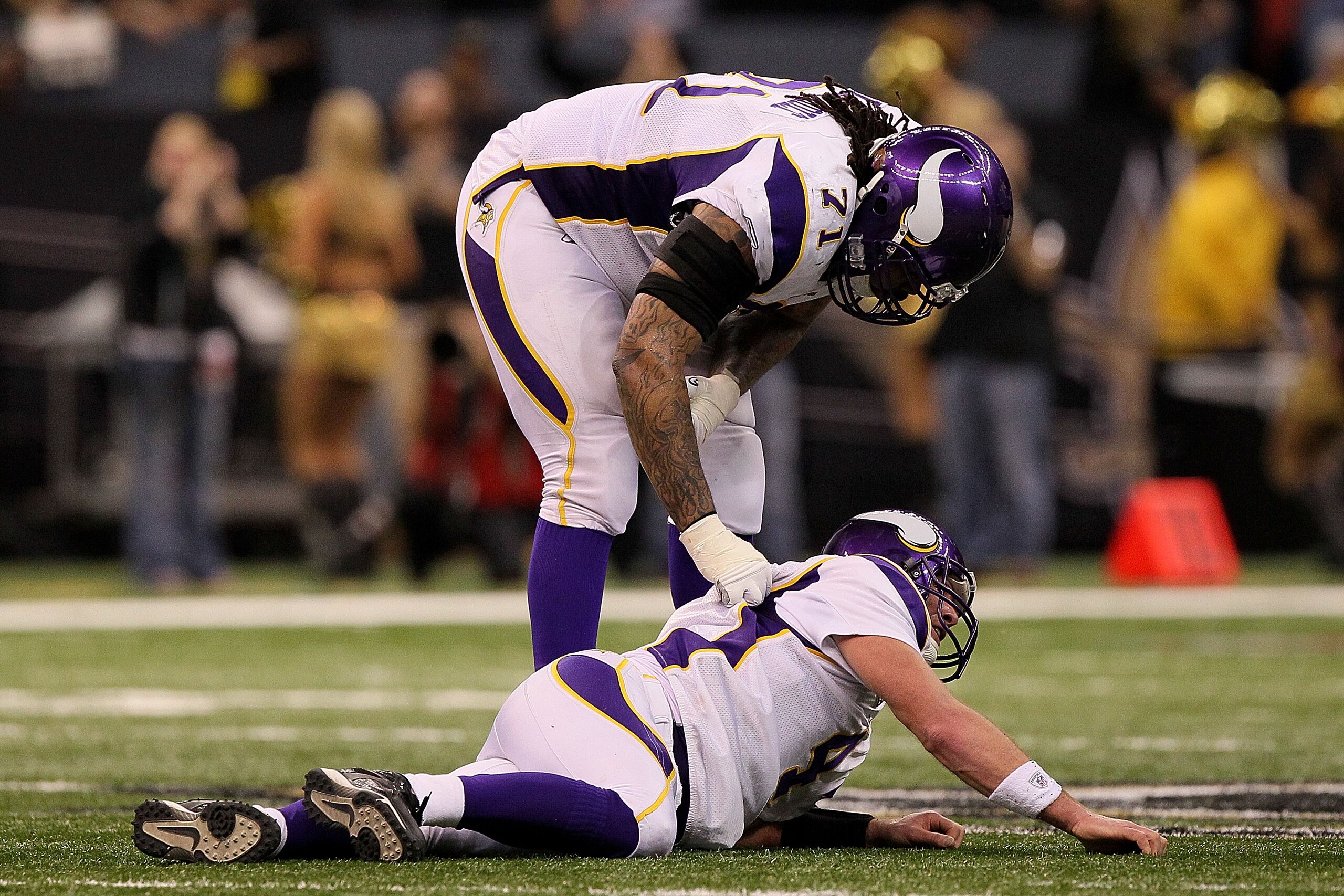 NEW ORLEANS - JANUARY 24:  Phil Loadholt #71 of the Minnesota Vikings checks on teammate Brett Favre #4 after he was injured on a play against the New Orleans Saints during the NFC Championship Game at the Louisiana Superdome on January 24, 2010 in New Or