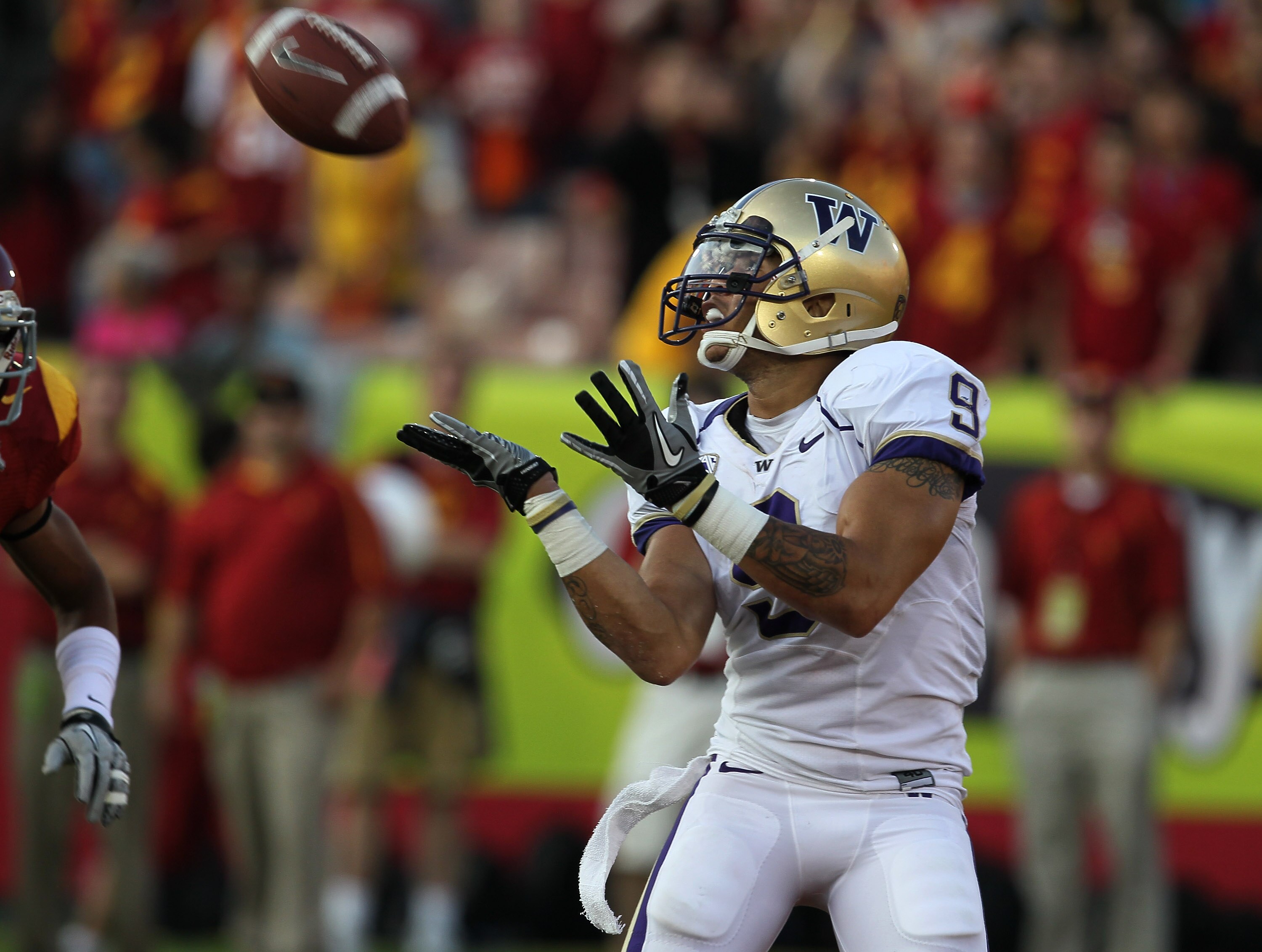 LOS ANGELES, CA - OCTOBER 02:  Wide Receiver Devin Aguilar #9 of the Washington Huskies catches a 44 yard touchdown pass in the end zone against cornerback Torin Harris #4 of the USC Trojans in the second quarter at the Los Angeles Memorial Coliseum on Oc