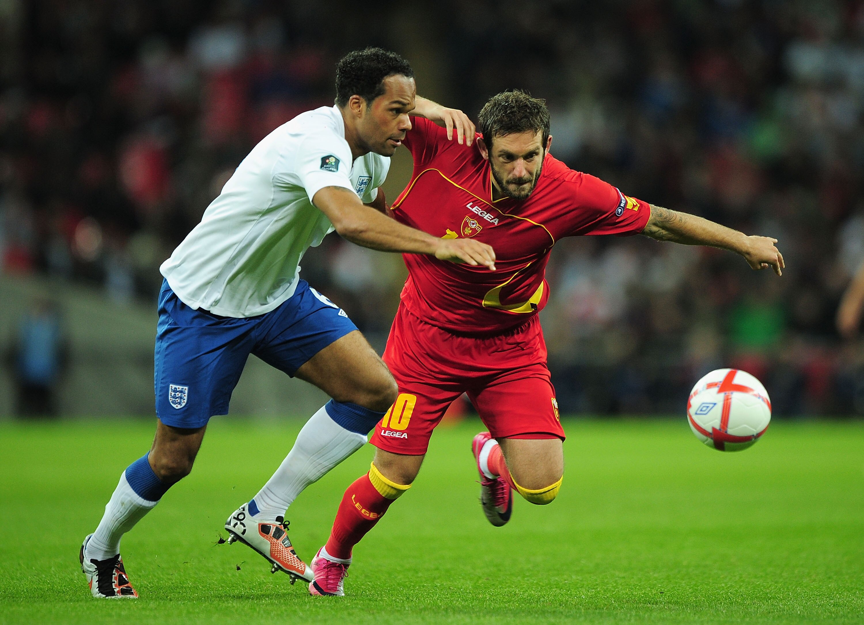LONDON, ENGLAND - OCTOBER 12:  Joeleon Lescott of England and Radomir Djalovic of Montenegro battle for the ball during the UEFA EURO 2012 Group G Qualifying match between England and Montenegro at Wembley Stadium on October 12, 2010 in London, England.  
