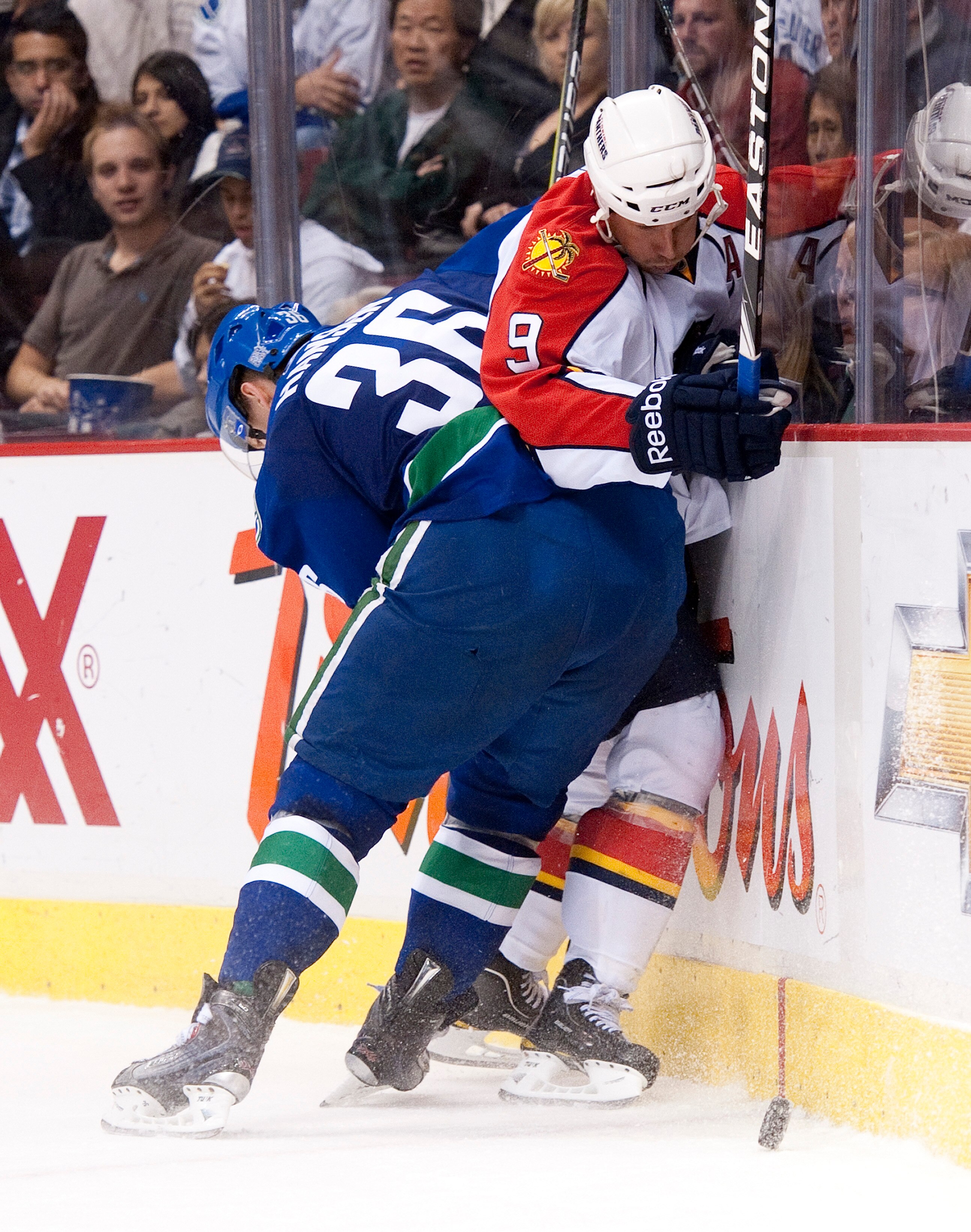 VANCOUVER, CANADA - OCTOBER 11: Jannik Hansen #36 of the Vancouver Canucks hits Stephen Weiss #9 of the Florida Panthers into the end boards during the third period in NHL action on October 11, 2010 at Rogers Arena in Vancouver, British Columbia, Canada.
