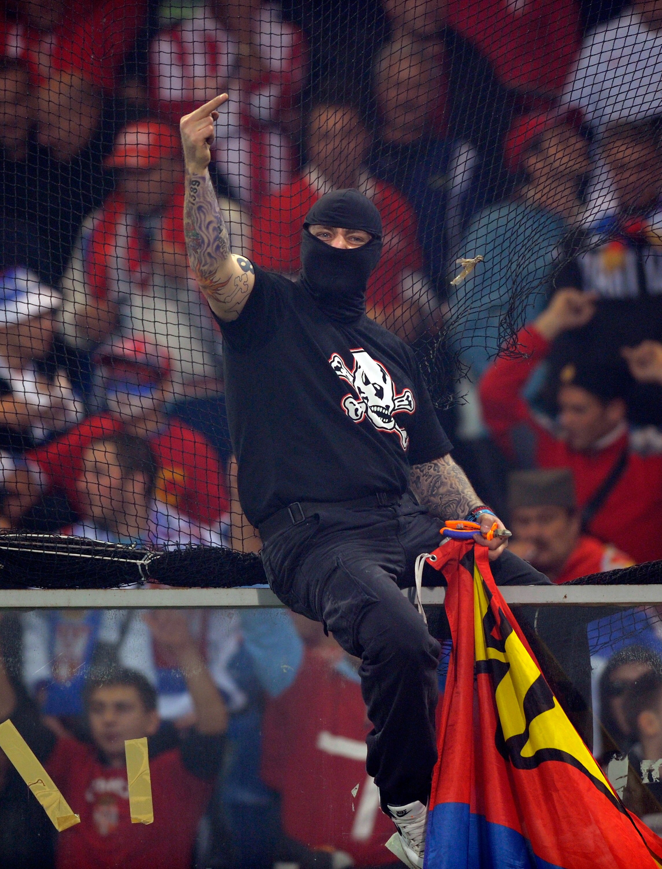 GENOA, ITALY - OCTOBER 12: Balaclava clad Serbian fan Ivan Bogdanov gestures towards riot police during the UEFA EURO 2012 Group C qualifier between Italy and Serbia at Luigi Ferraris Stadium on October 12, 2010 in Genoa, Italy. (Photo by Claudio Villa/Ge