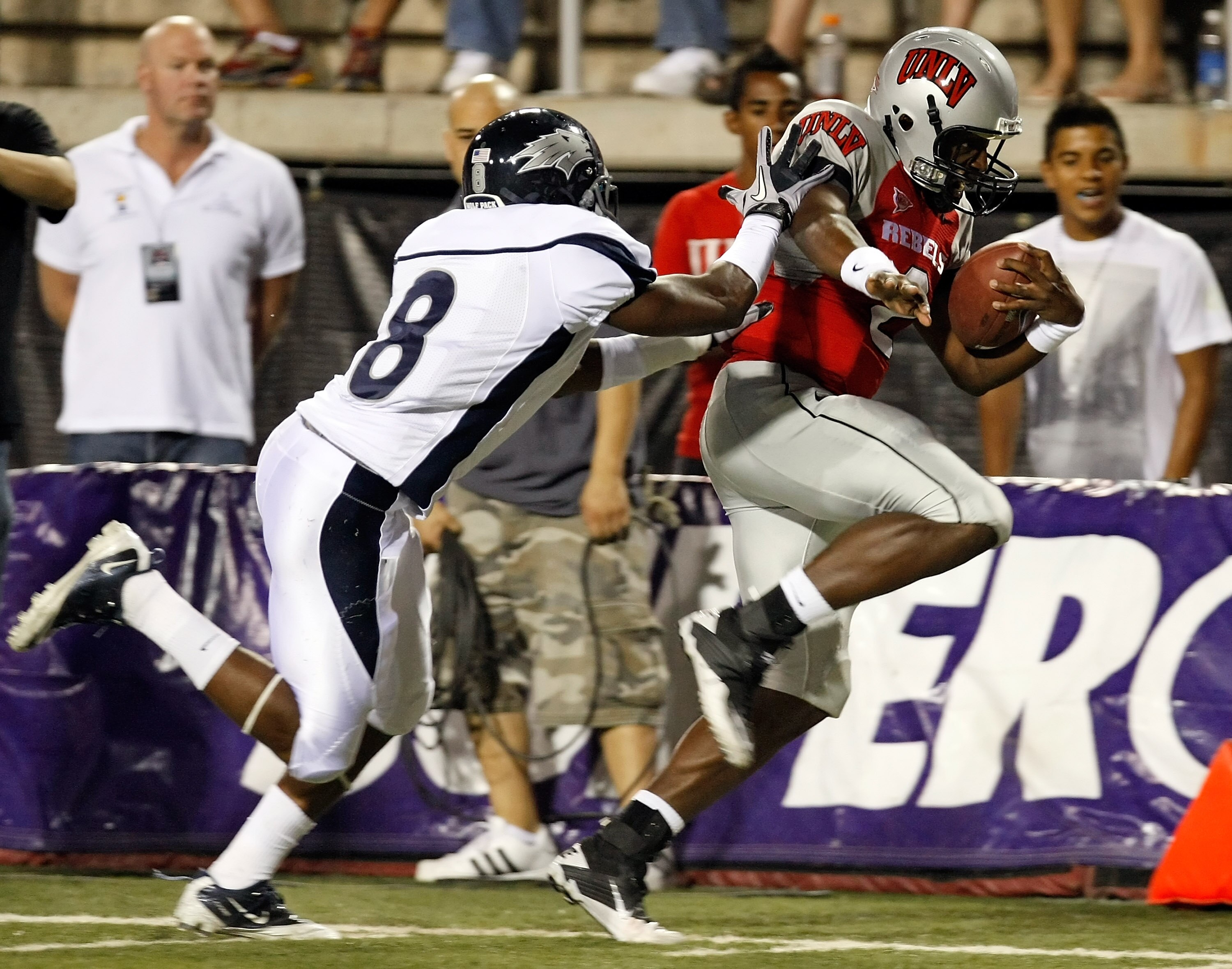 LAS VEGAS - OCTOBER 02:  Marlon Johnson #8 of the Nevada Reno Wolf Pack pushes quarterback Omar Clayton #2 of the UNLV Rebels out of bounds as he runs for yardage in the second quarter of their game at Sam Boyd Stadium October 2, 2010 in Las Vegas, Nevada