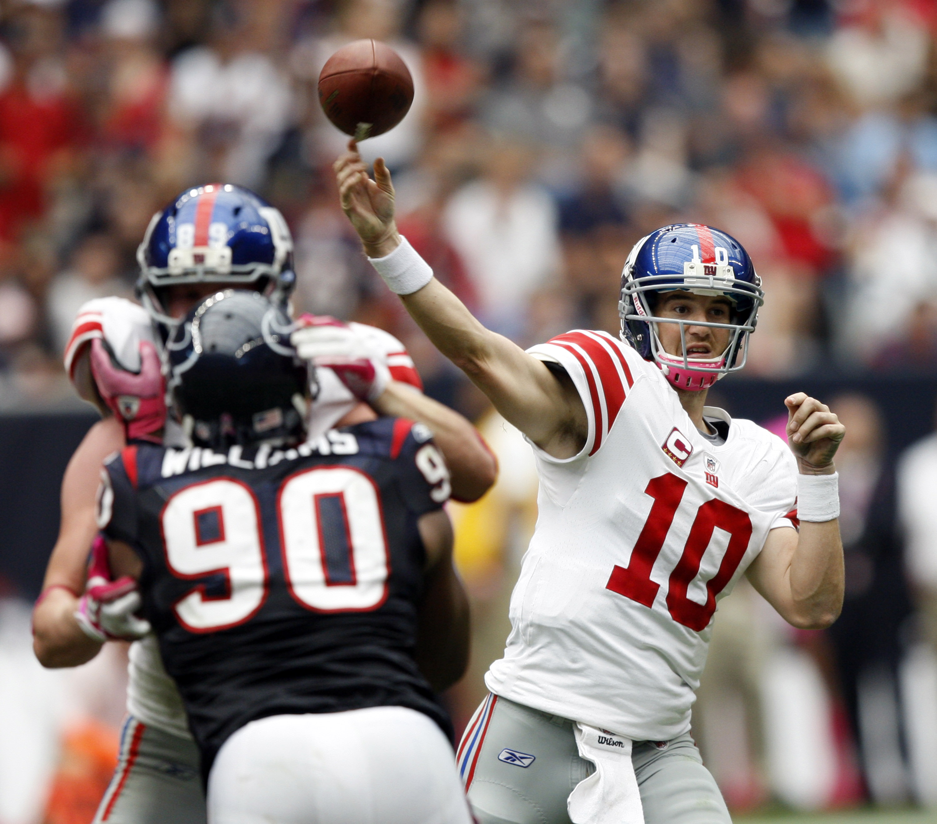 HOUSTON - OCTOBER 10:  Quarterback Eli Manning #10 of the New York Giants throws downfield before defensive end Mario Williams #90 can get to him at Reliant Stadium on October 10, 2010 in Houston, Texas. New York won 34-10.  (Photo by Bob Levey/Getty Imag