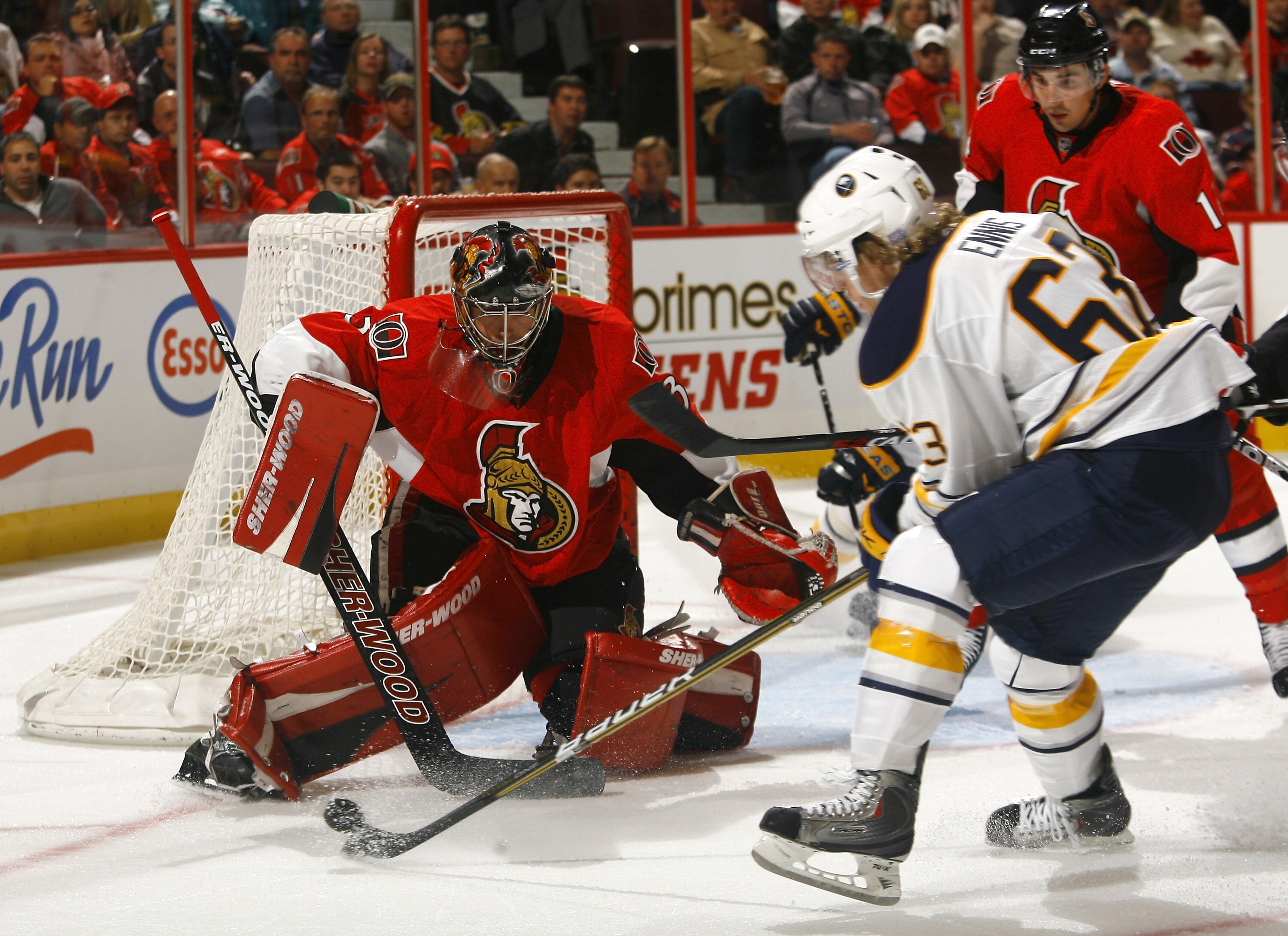 OTTAWA, CANADA - OCTOBER 08:   Tyler Ennis #63 of the Buffalo Sabres tries to control a loose puck at the side of the crease while Pascal Leclaire #33 of the Ottawa Senators slides over to cover his net during a game at Scotiabank Place on October 8, 2010