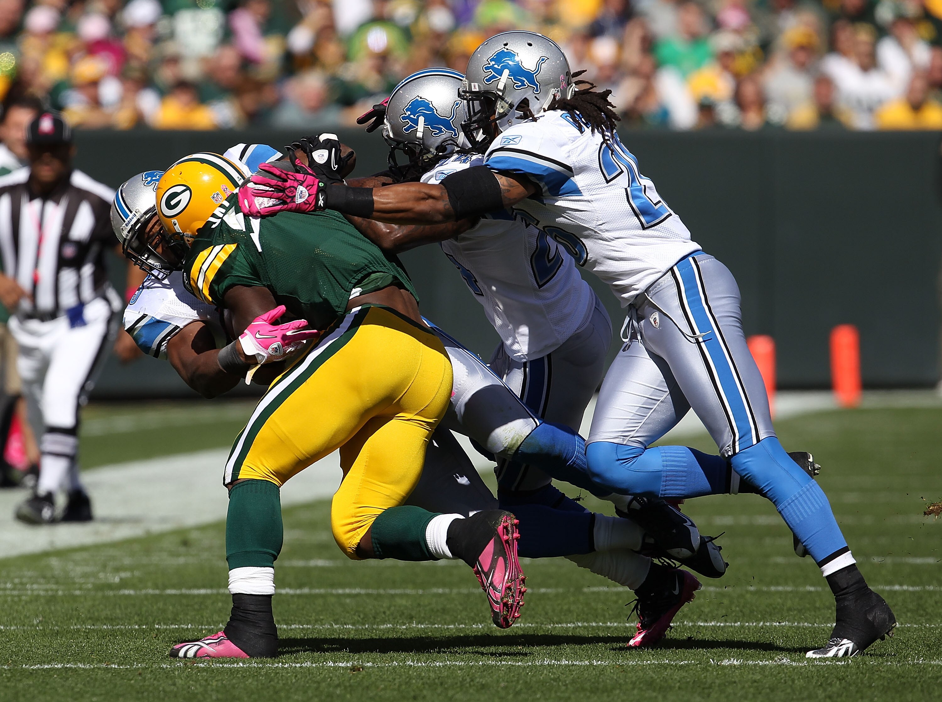 GREEN BAY, WI - OCTOBER 03: Brandon Jackson #32 of the Green Bay Packers is tackled by members of the Detroit Lion defense including Jonathan Wade #24 and Louis Delmas #26 at Lambeau Field on October 3, 2010 in Green Bay, Wisconsin. The Packers defeated t