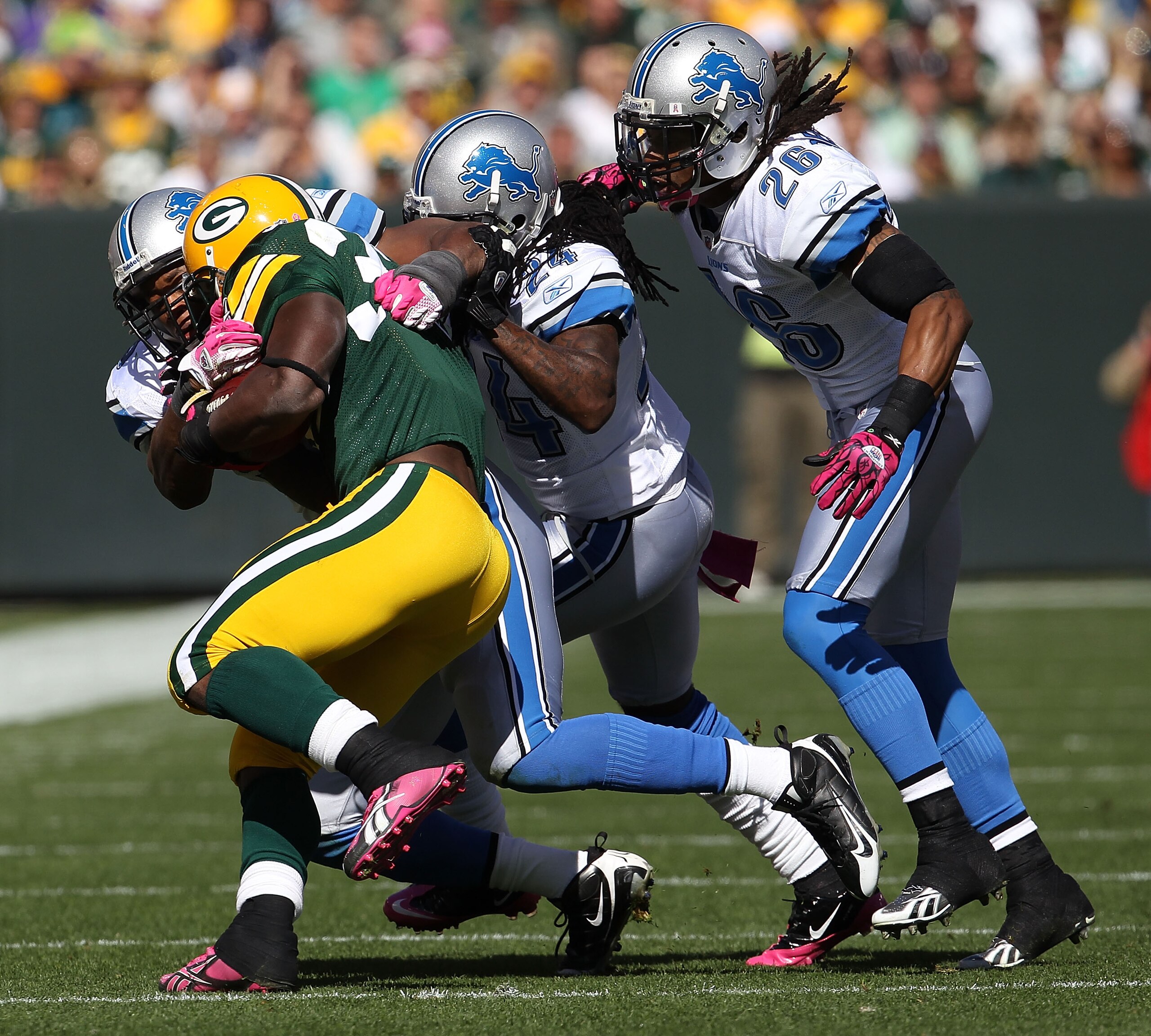 GREEN BAY, WI - OCTOBER 03: Brandon Jackson #32 of the Green Bay Packers is tackled by members of the Detroit Lion defense including Jonathan Wade #24 and Louis Delmas #26 at Lambeau Field on October 3, 2010 in Green Bay, Wisconsin. The Packers defeated t