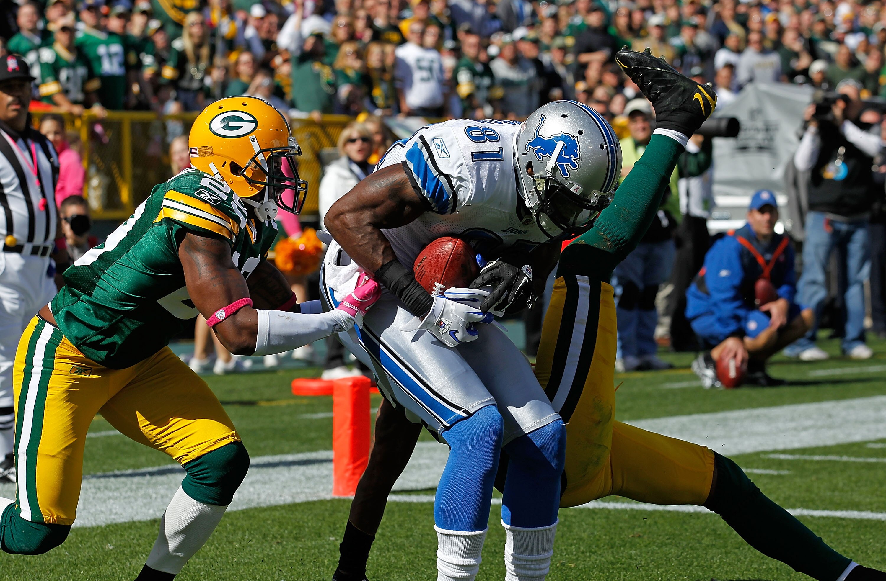 GREEN BAY, WI - OCTOBER 03: Calvin Johnson #81 of the Detroit Lions drops to the end zone after catching a touchdown pass between Derrick Martin #29 and Charles Woodson #21 of the Green Bay Packers at Lambeau Field on October 3, 2010 in Green Bay, Wiscons