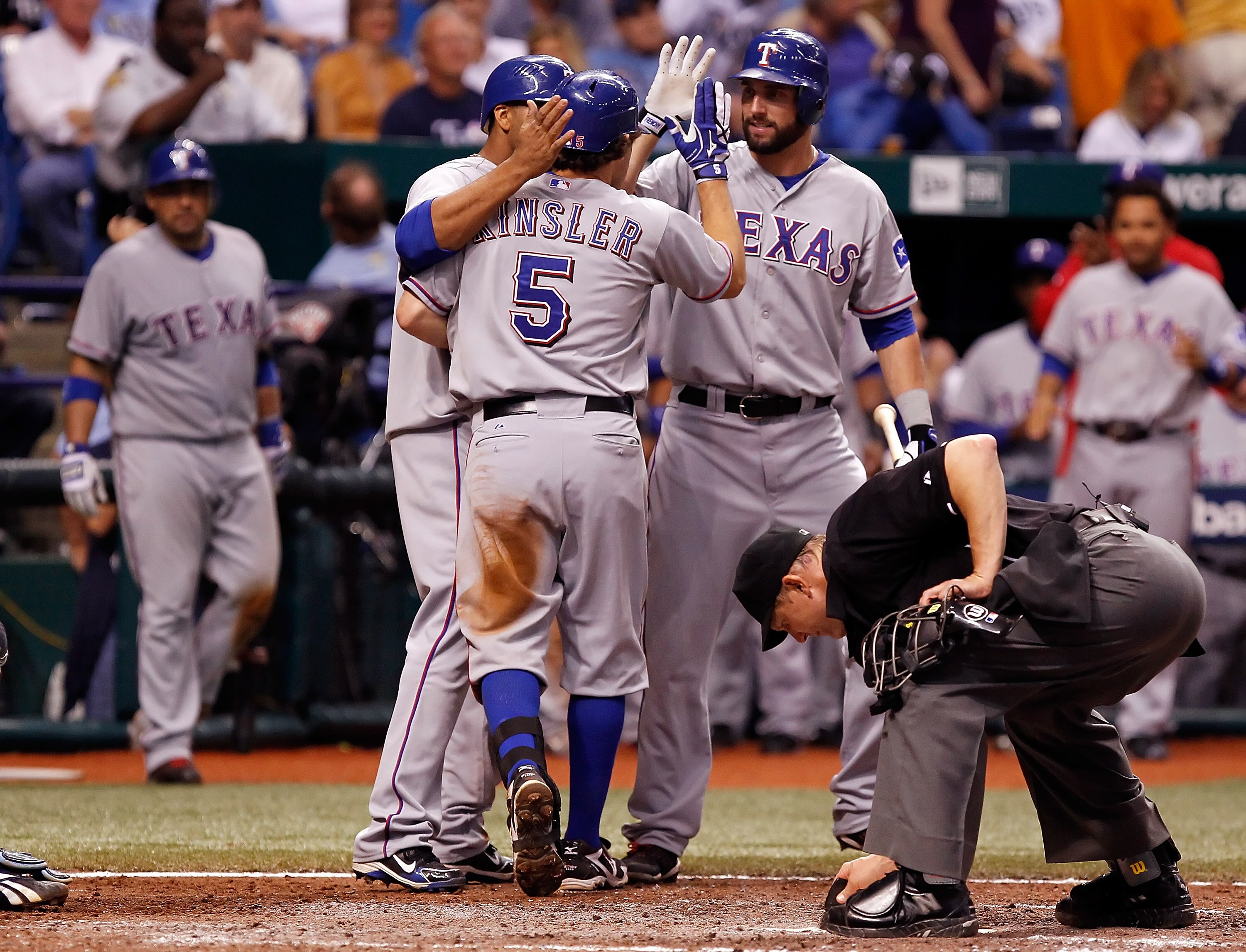 ST. PETERSBURG, FL - OCTOBER 12:  Infielder Ian Kinsler #5 of the Texas Rangers is congratulated at home plater by Nelson Cruz #17 (left) and Jeff Francoeur #21 after his home run against the Tampa Bay Rays during Game 5 of the ALDS at Tropicana Field on