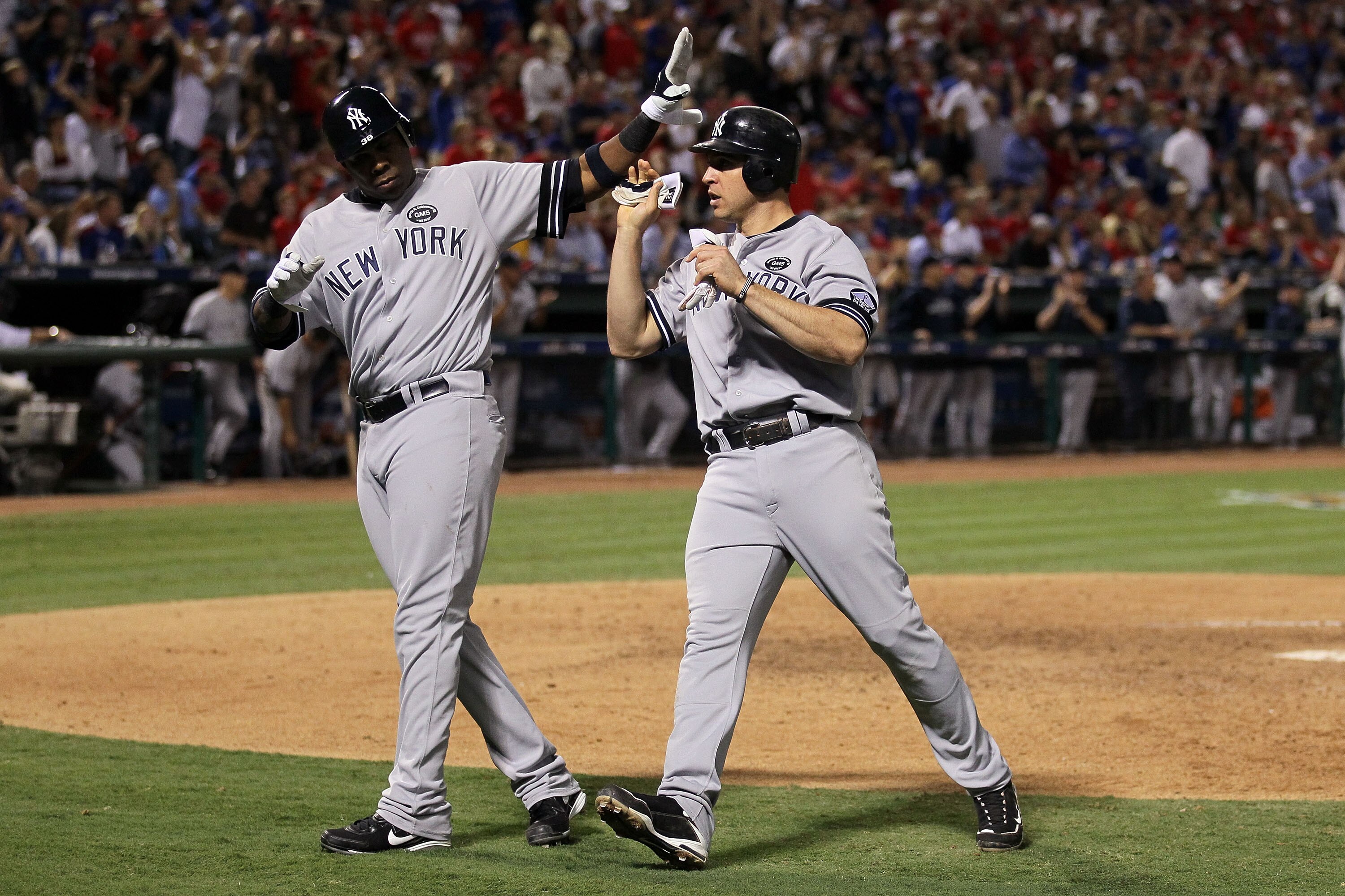 ARLINGTON, TX - OCTOBER 15:  Mark Teixeira (R) #25 of the New York Yankees is congratulated by Marcus Thames #38 after Teixeira scored in the top of the eighth inning against the Texas Rangers in Game One of the ALCS during the 2010 MLB Playoffs at Ranger