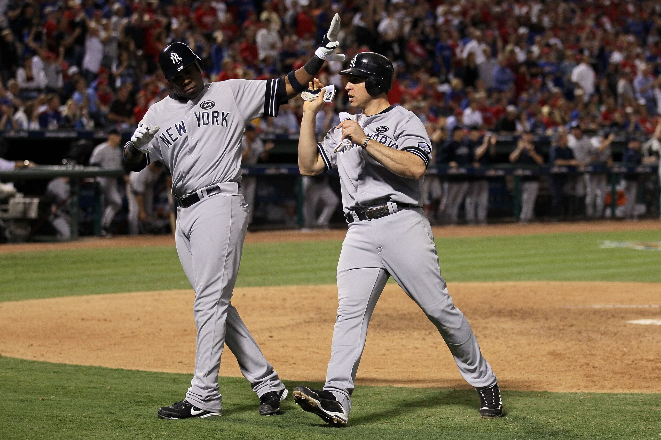 ARLINGTON, TX - OCTOBER 15:  Mark Teixeira (R) #25 of the New York Yankees is congratulated by Marcus Thames #38 after Teixeira scored in the top of the eighth inning against the Texas Rangers in Game One of the ALCS during the 2010 MLB Playoffs at Ranger