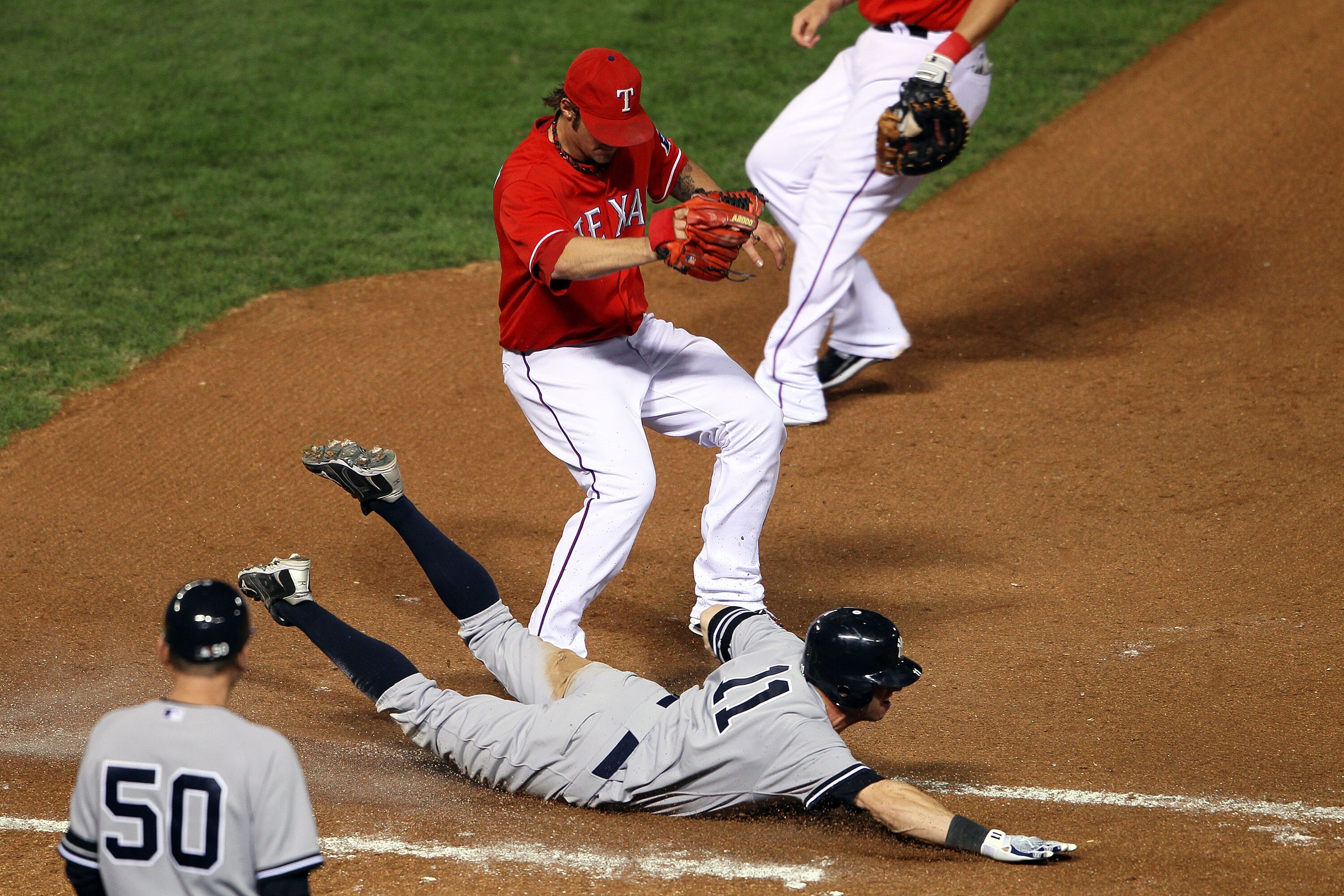 ARLINGTON, TX - OCTOBER 15:  Brett Gardner #11 of the New York Yankees slides into first safely ahead of the tag of pitcher C.J. Wilson #36 of the Texas Rangers in Game One of the ALCS during the 2010 MLB Playoffs at Rangers Ballpark in Arlington on Octob