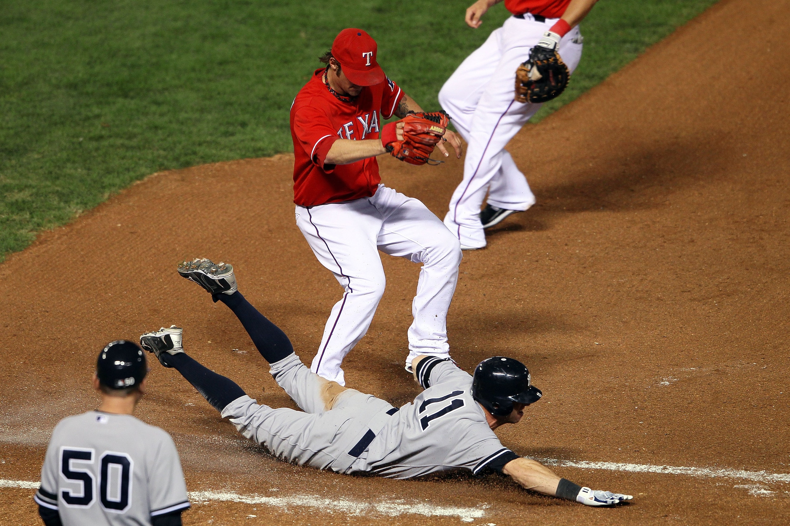 ARLINGTON, TX - OCTOBER 15:  Brett Gardner #11 of the New York Yankees slides into first safely ahead of the tag of pitcher C.J. Wilson #36 of the Texas Rangers in Game One of the ALCS during the 2010 MLB Playoffs at Rangers Ballpark in Arlington on Octob