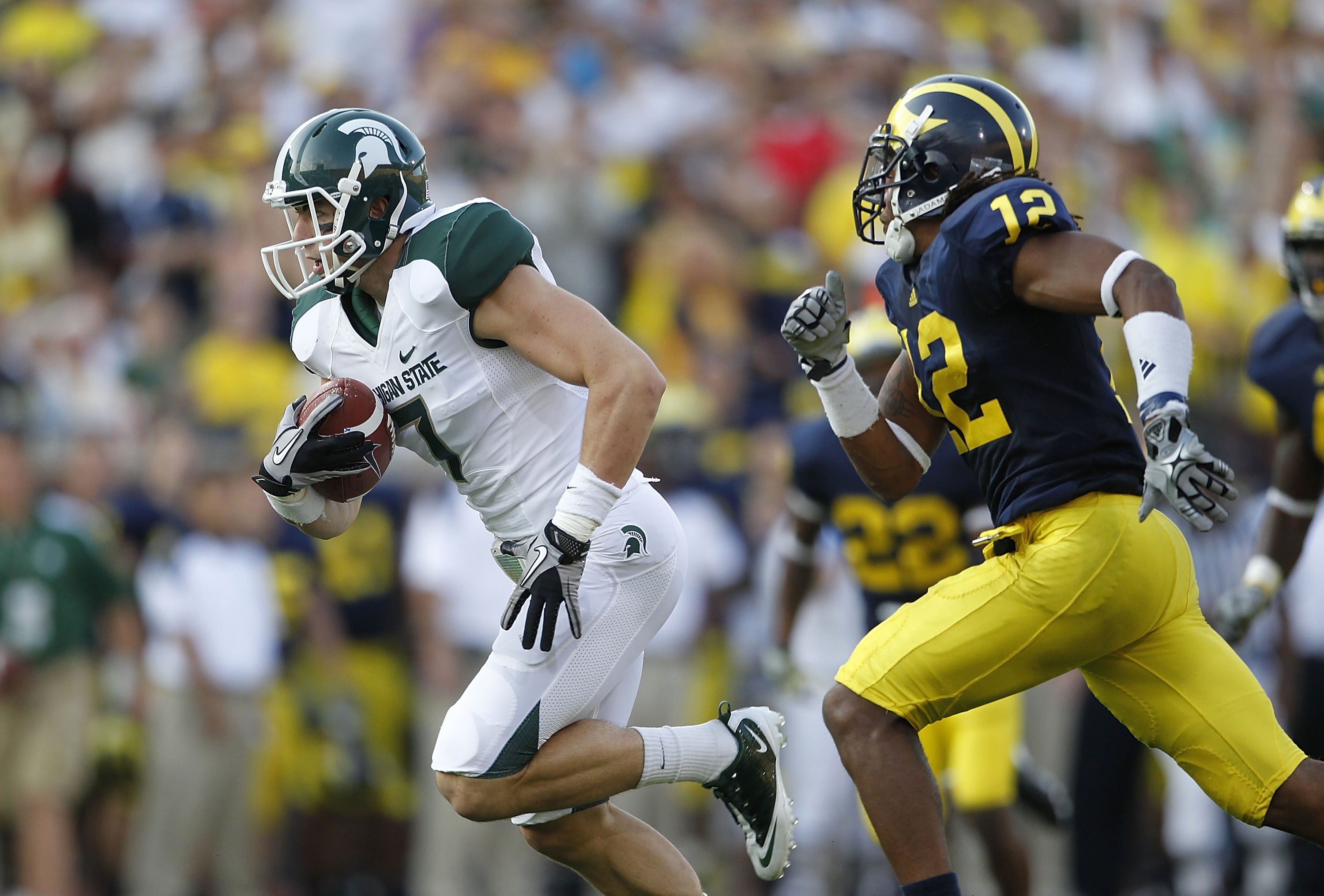 ANN ARBOR, MI - OCTOBER 09:  Steve Nichol #7 of the Michigan State Spartans runs past J. T. Floyd #12 of the Michigan Wolverines after catching a 42 yard pass compleation from Kirk Cousins #8 during the third quarter of the game against the Michigan Wolve