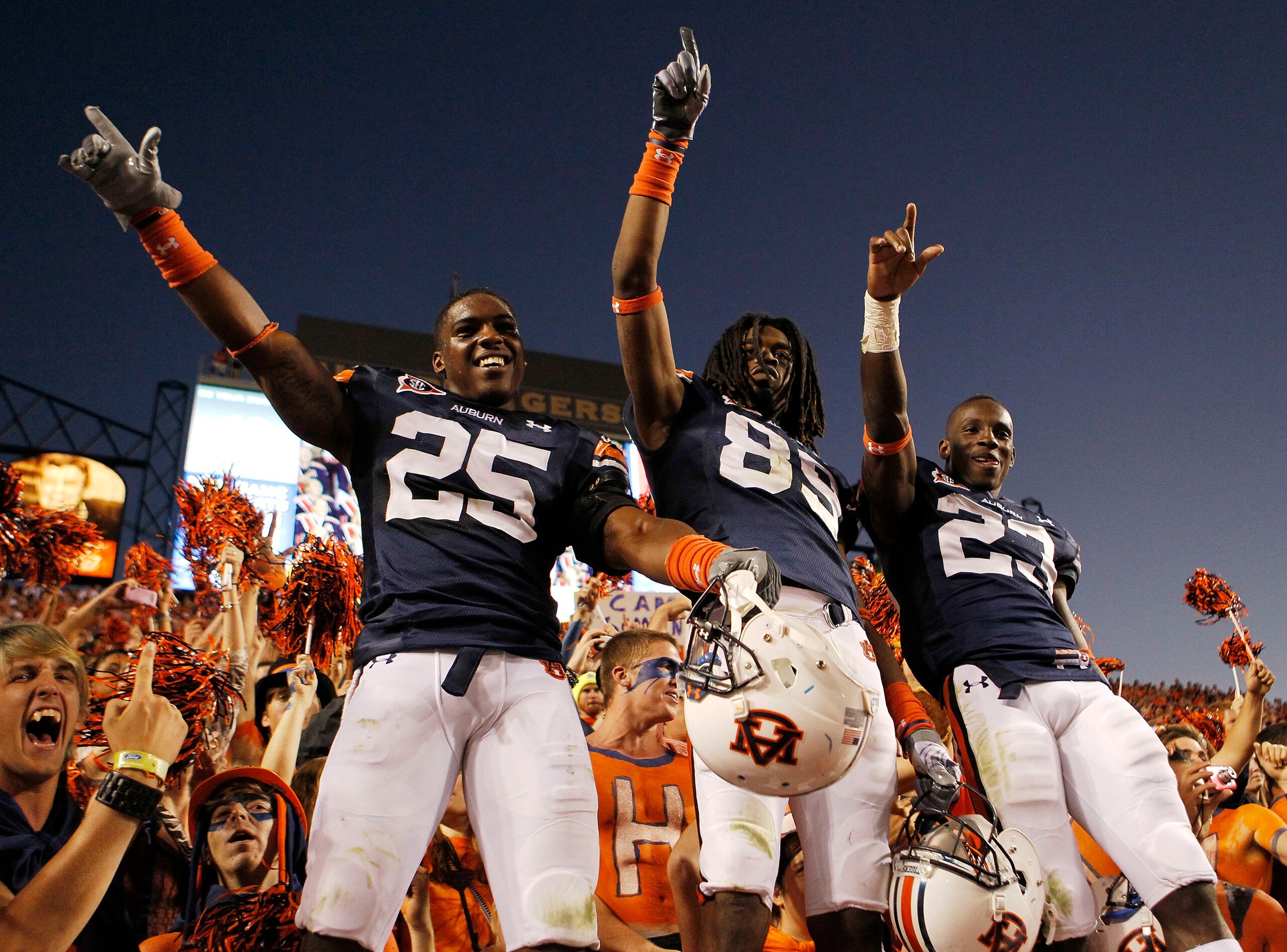 AUBURN - OCTOBER 16:  Linebacker Daren Bates #25, wide receiver Darvin Adams #89 and running back Onterio McCalebb #23 of the Auburn Tigers celebrate with the crowd after the game against the Arkansas Razorbacks at Jordan-Hare Stadium on October 16, 2010
