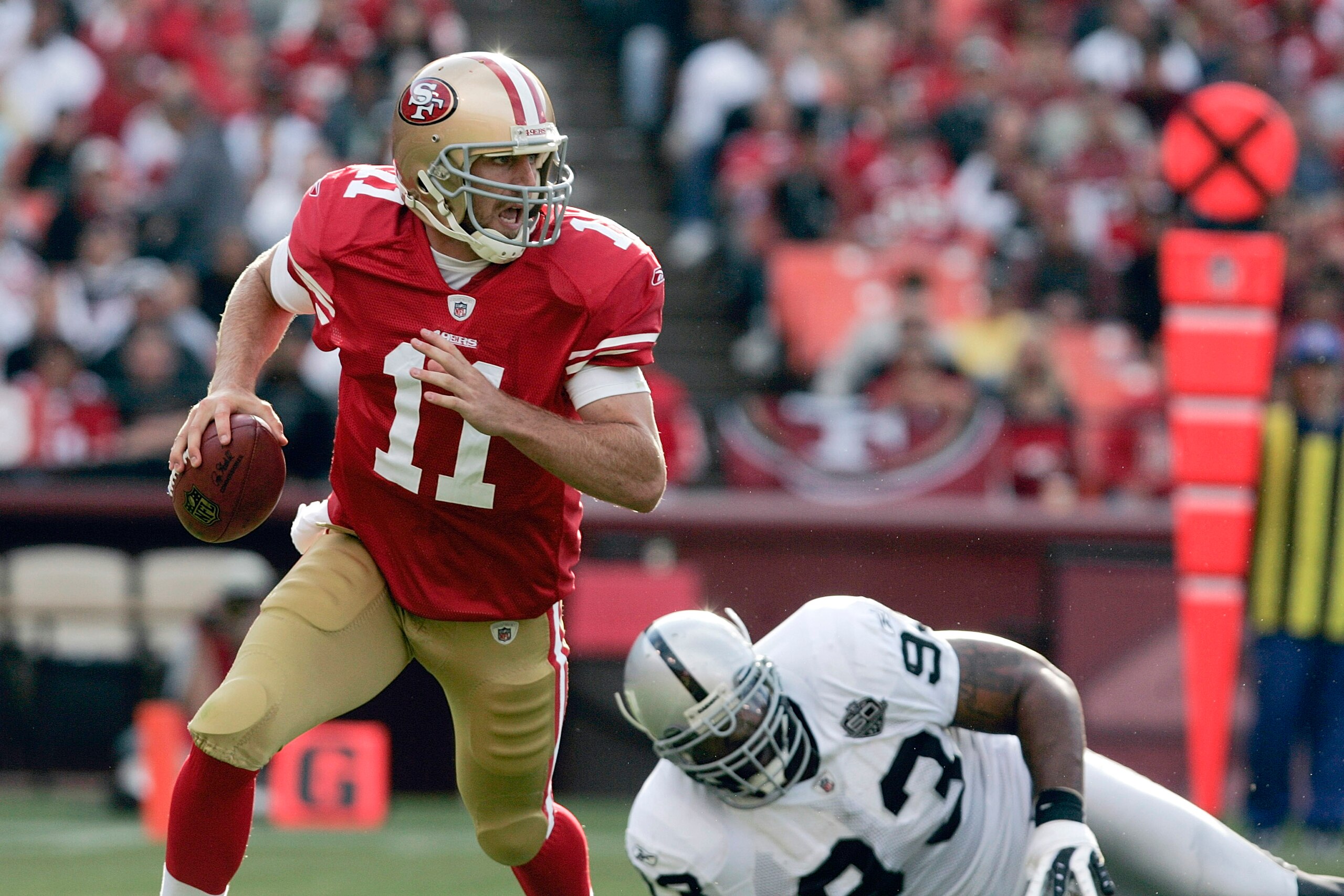 SAN FRANCISCO - AUGUST 22:   San Francisco 49ers quarterback Alex Smith #11 scrambles away from Oakland Raiders defensive end Tommy Kelly #93 during the 1st quarter as the San Francisco 49ers host the Oakland Raiders at Candlestick Park August 22, 2009 in