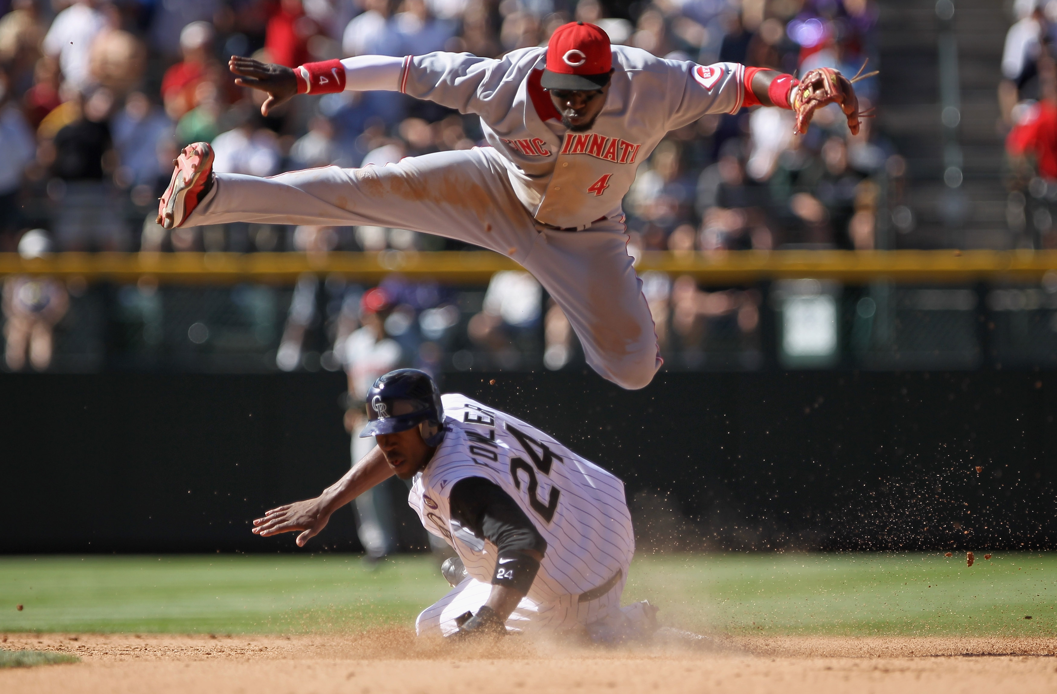 DENVER - SEPTEMBER 09:  Second baseman Brandon Phillips #4 of the Cincinnati Reds leaps over Dexter Fowler #24 of the Colorado Rockies as he turns a double play on Carlos Gonzalez in the seventh inning at Coors Field on September 9, 2010 in Denver, Colora
