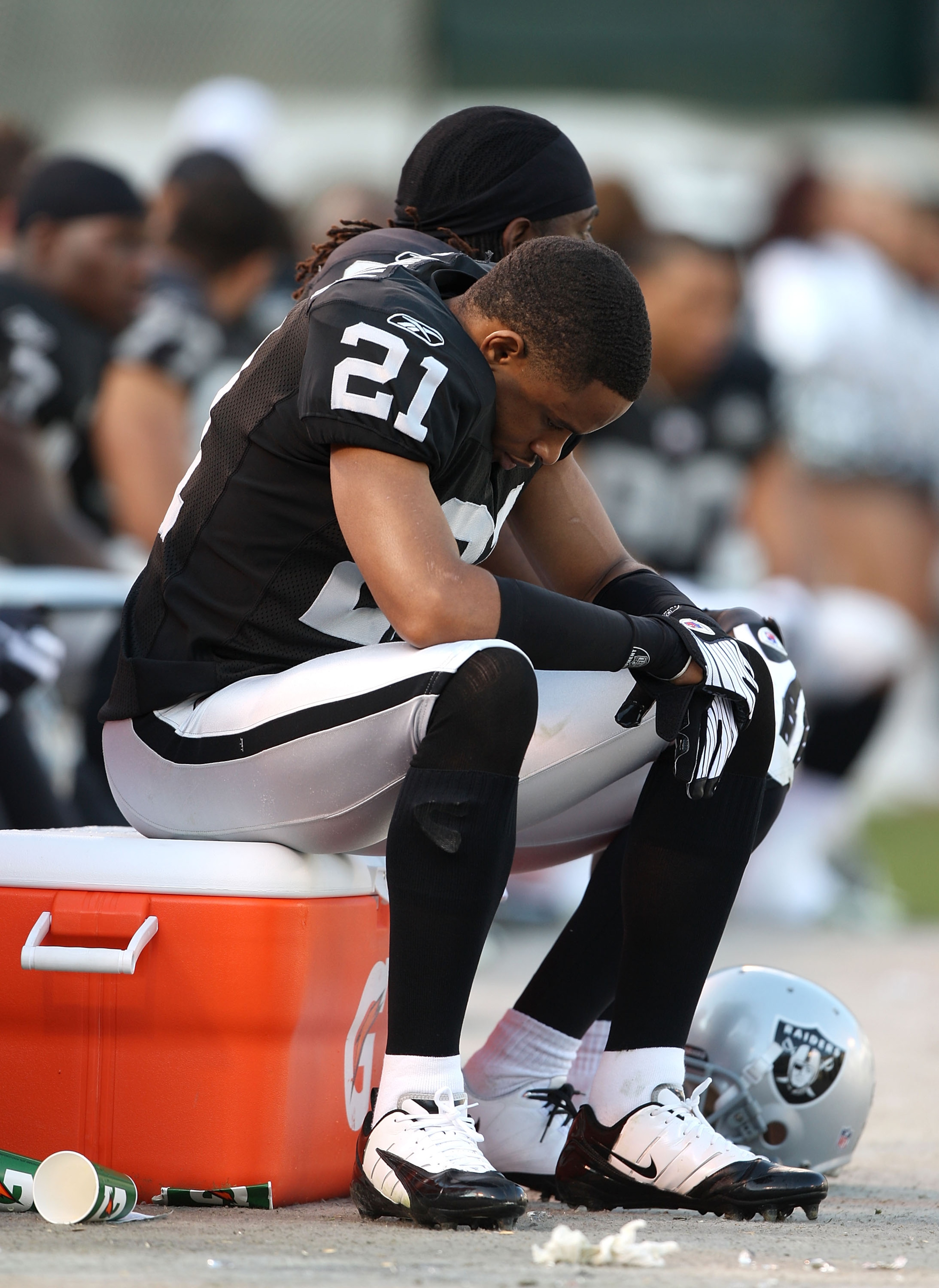 OAKLAND, CA - JANUARY 3:  Nnamdi Asomugha #21 of the Oakland Raiders sits on the bench against the Baltimore Ravens during an NFL game at Oakland-Alameda County Coliseum on January 3, 2010 in Oakland, California. (Photo by Jed Jacobsohn/Getty Images)