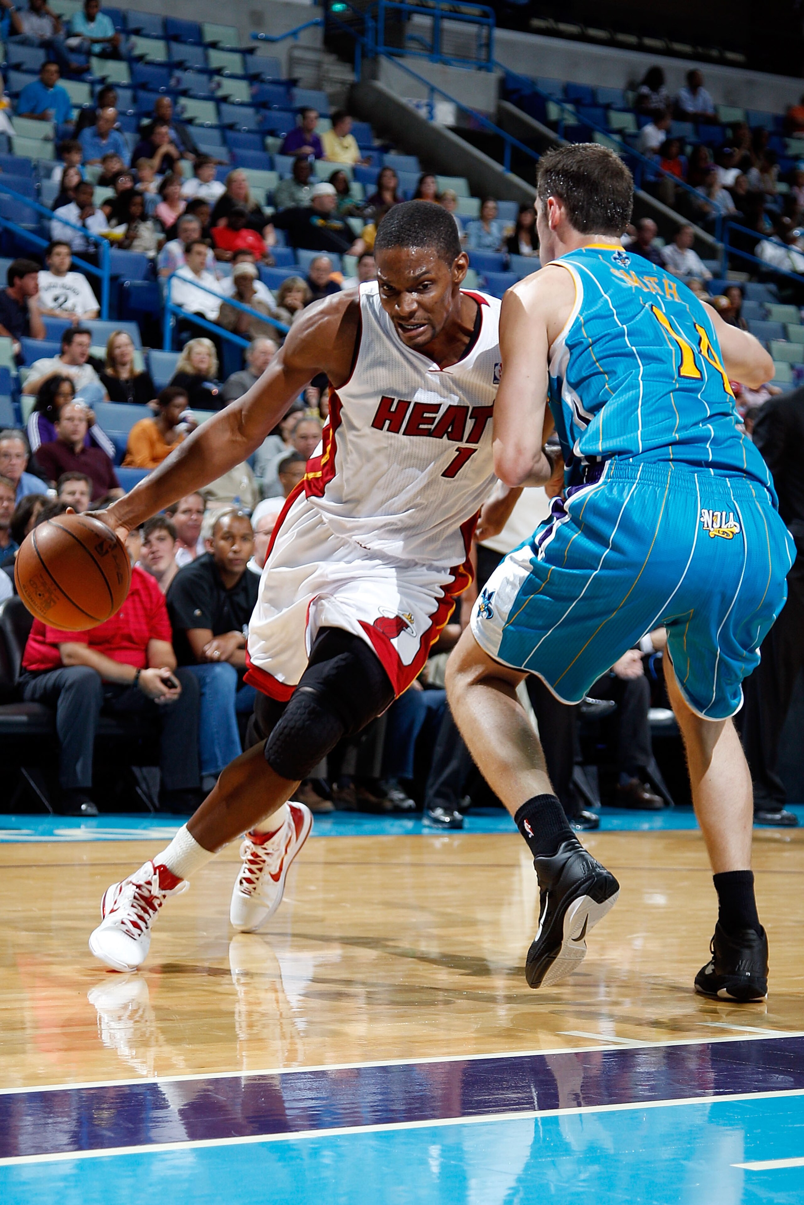 NEW ORLEANS - OCTOBER 13:  Chris Bosh #1 of the Miami Heat drives the ball around Jason Smithe #14 of the New Orleans Hornets at the New Orleans Arena on October 13, 2010 in New Orleans, Louisiana.  The Hornets defeated the Heat 90-76.   NOTE TO USER: Use