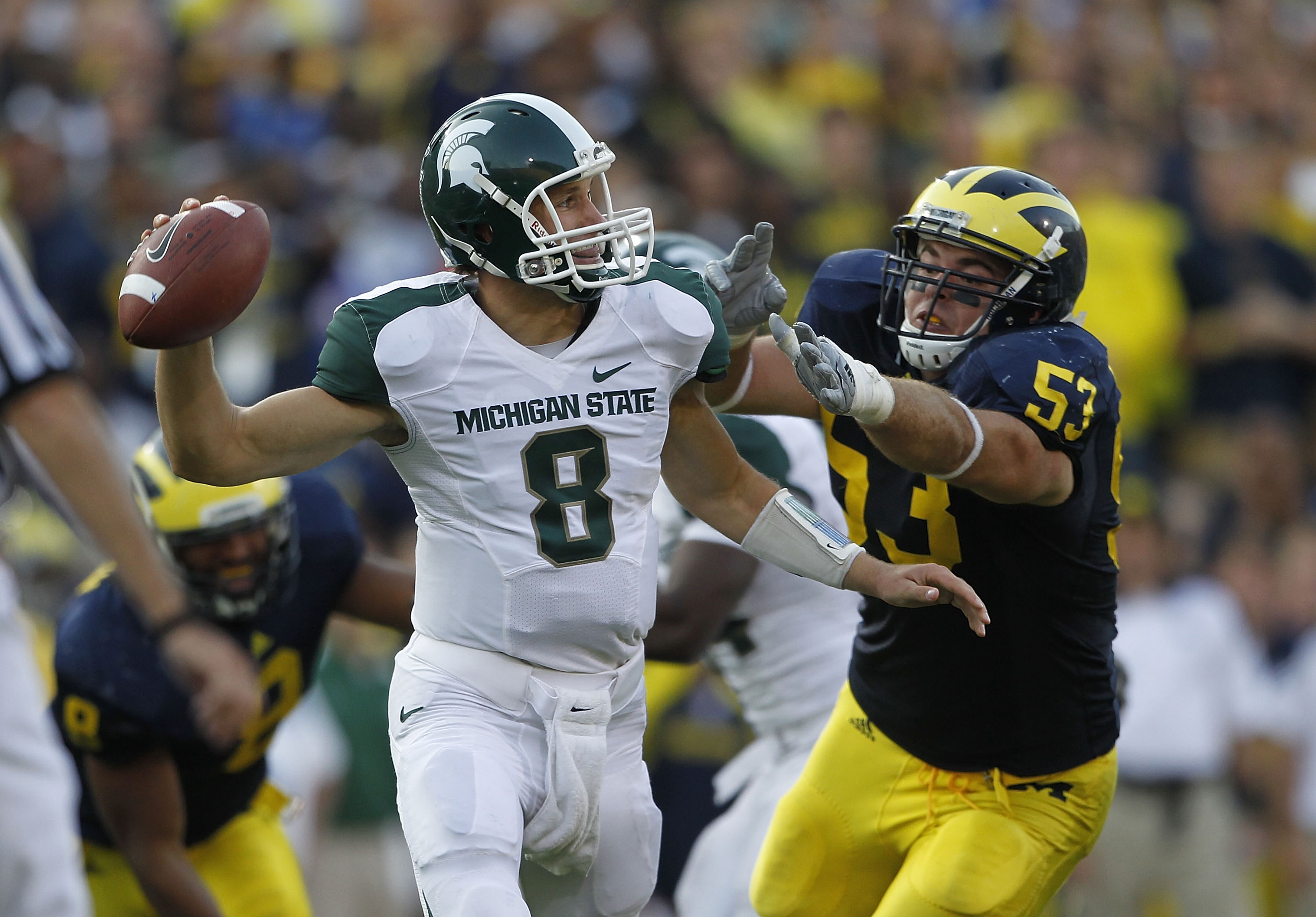 ANN ARBOR, MI - OCTOBER 09:  Kirk Cousins #8 of the Michigan State Spartans rolls out to pass as Ryan Van Bergen #53 of the Michigan Wolverines attempts to make the sack during the game on October 9, 2010 at Michigan Stadium in Ann Arbor, Michigan. The Mi