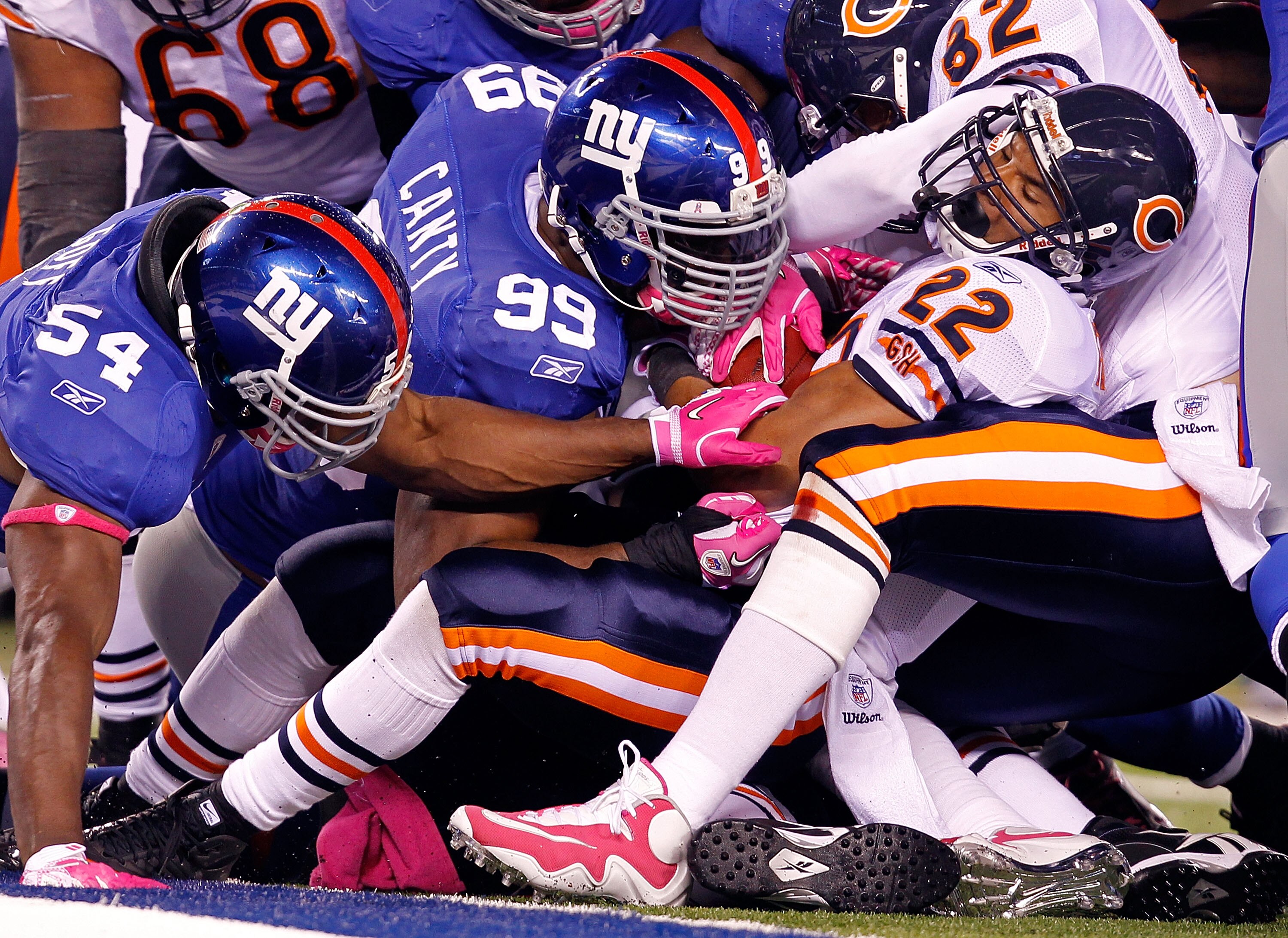 EAST RUTHERFORD, NJ - OCTOBER 03:  Matt Forte #22 of the Chicago Bears is tackled by Jonathan Goff #54 and Chris Canty #99 of the New York Giants at New Meadowlands Stadium on October 3, 2010 in East Rutherford, New Jersey.  (Photo by Michael Heiman/Getty