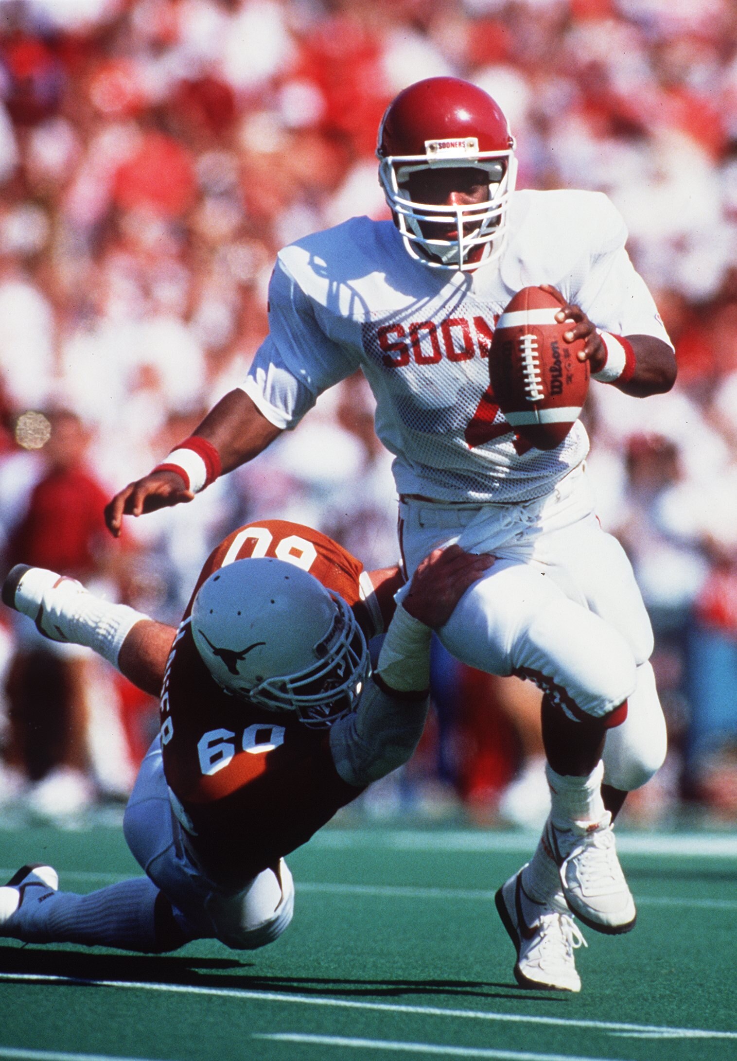 1988:  OKLAHOMA QUARTERBACK JAMELLE HOLIEWAY BREAKS THE TACKLE OF A TEXAS DEFENDER DURING THE SOONERS GAME VERSUS THE LONGHORNS AT THE COTTON BOWL IN DALLAS, TEXAS. Mandatory Credit: Allen Steele/ALLSPORT