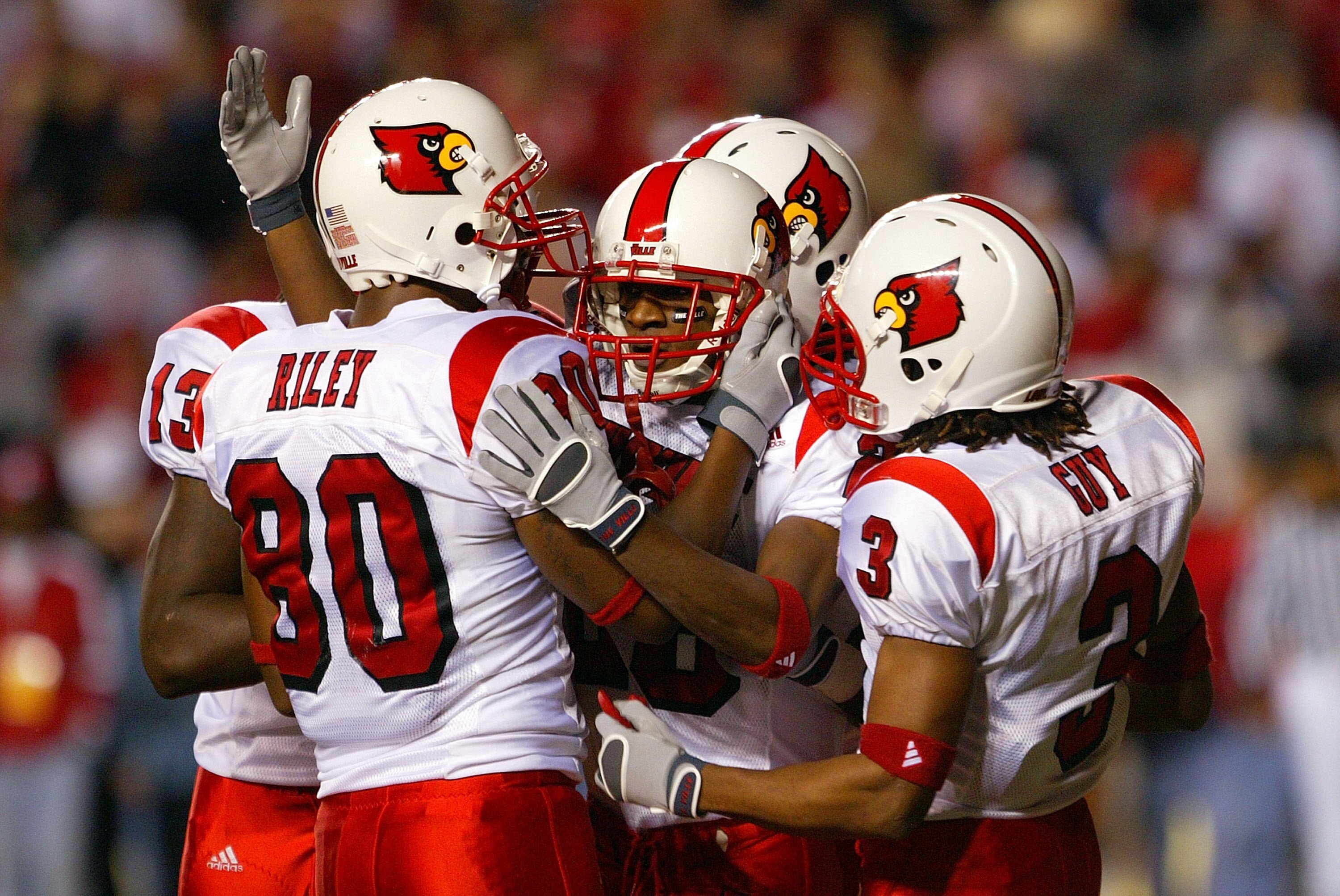 PISCATAWAY, NJ - NOVEMBER 09:  JaJuan Spillman #26 of the Louisville Cardinals celebrates with Jimmy Riley #80 and Trent Guy #3 after running back a kickoff for a touchdown against the Rutgers Scarlet Knights in teh first quarter at Rutgers Stadium on Nov