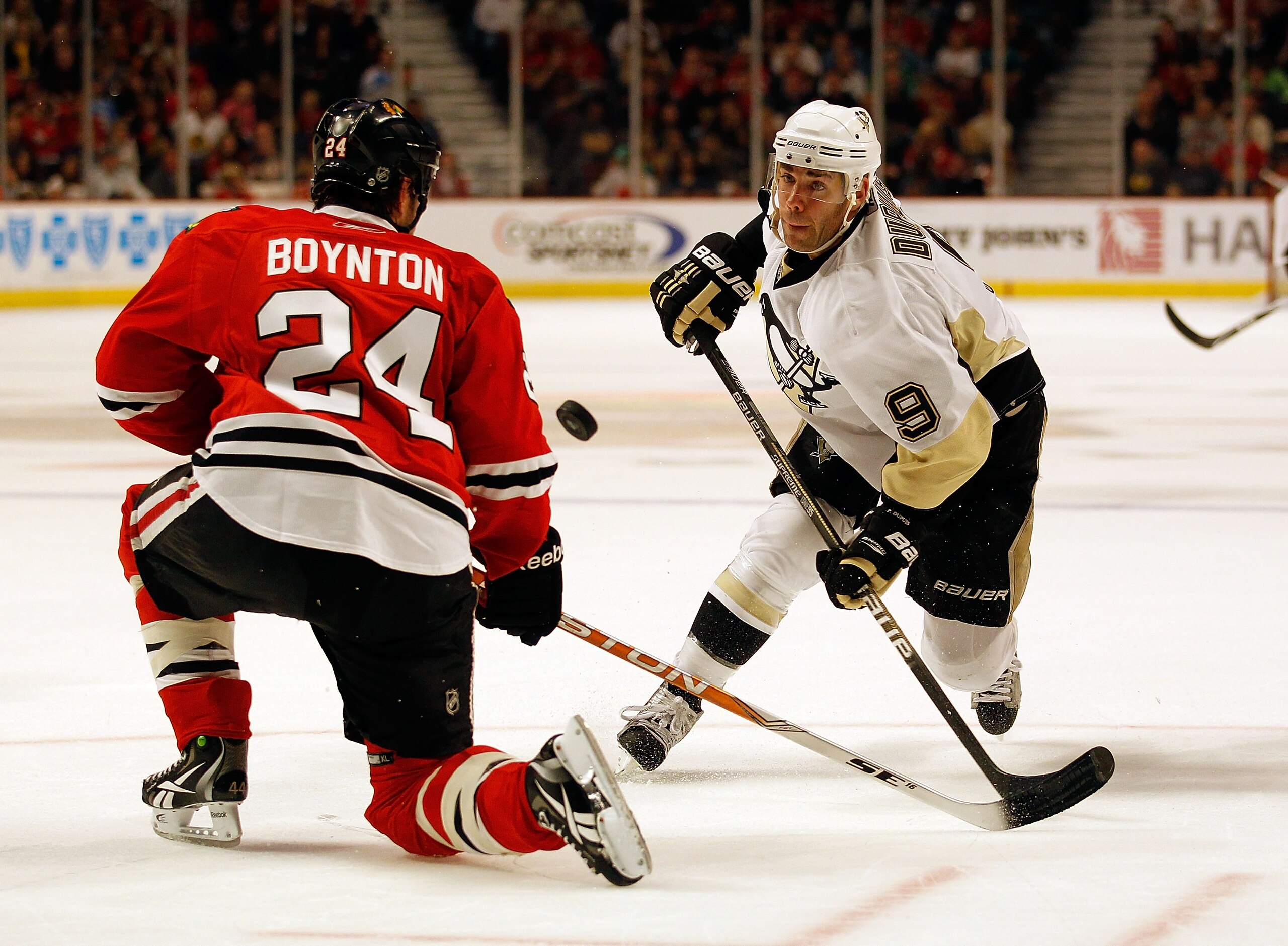 CHICAGO - OCTOBER 01: Pascal Dupuis #9 of the Pittsburgh Penguins and Nick Boynton #24 of the Chicago Blackhawks battle for the puck during a pre-season game at the United Center on October 1, 2010 in Chicago, Illinois. The Blackhawks defeated the Penguin