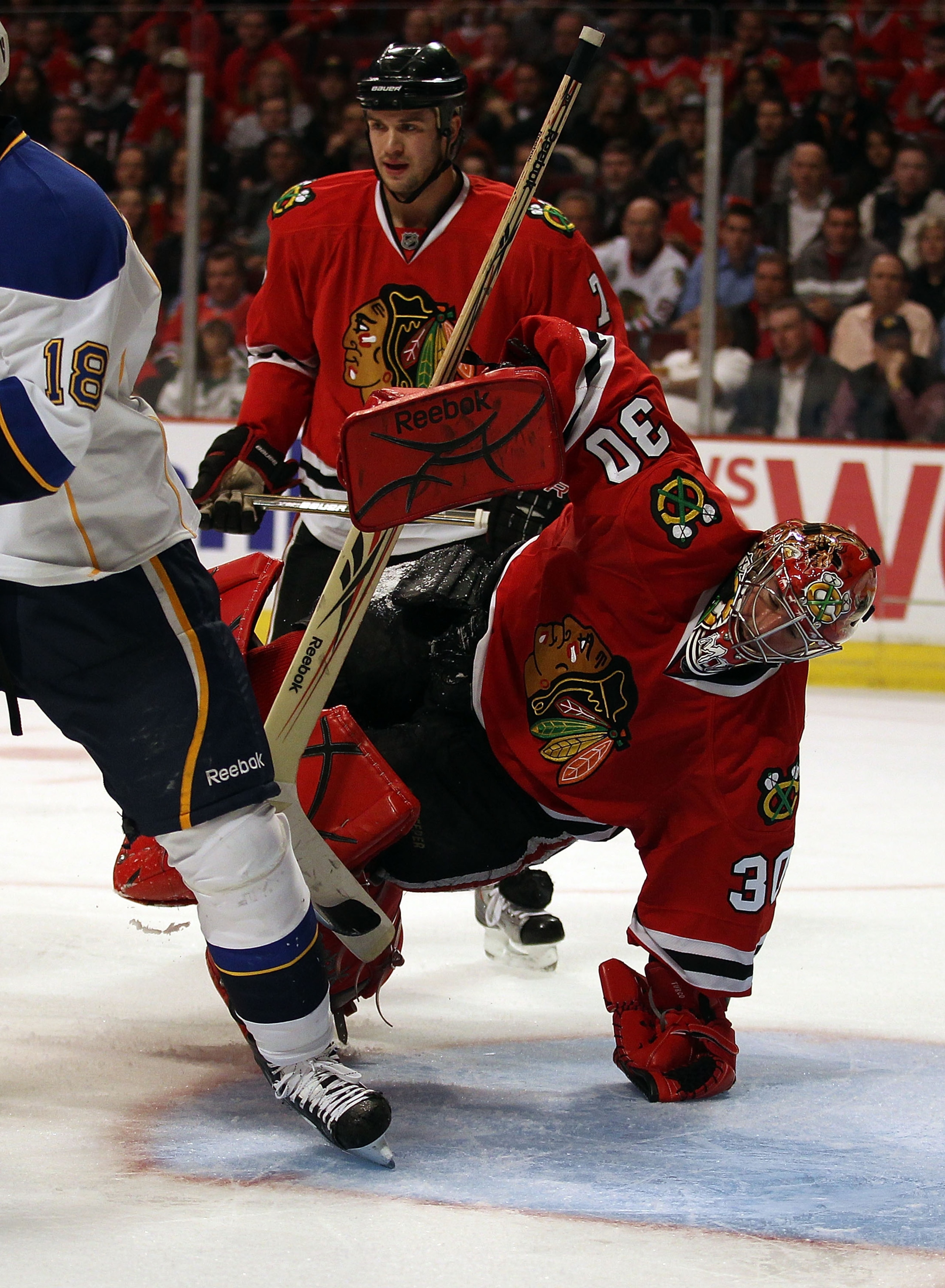 CHICAGO - OCTOBER 18: Marty Turco #30 of the Chicago Blackhawks turns on his hand to face a play against the St. Louis Blues as teammate Brett Seabrook #7 watches at the United Center on October 18, 2010 in Chicago, Illinois. The Blackhawks defeated the B