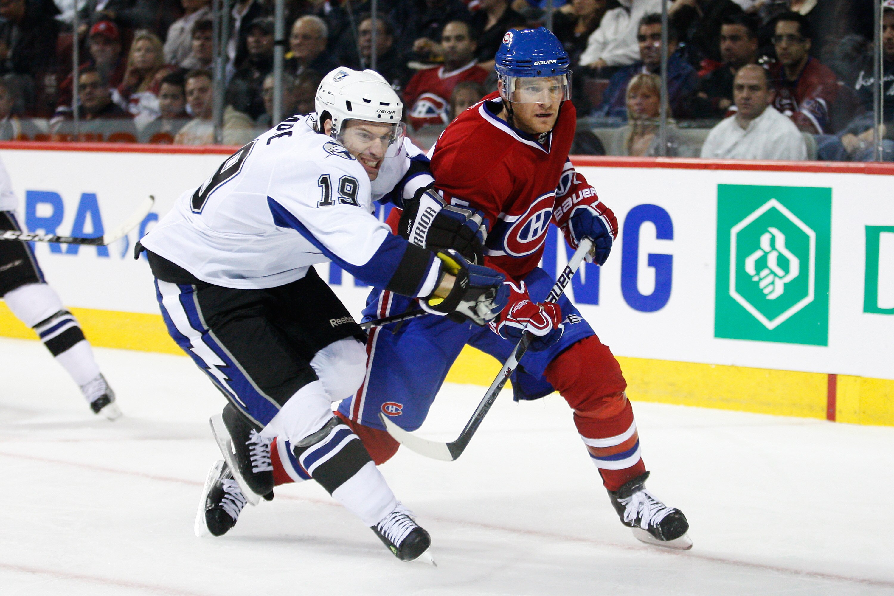 MONTREAL, CANADA - OCTOBER 13:  Dominic Moore #19 of the Tampa Bay Lightning and Jeff Halpern #15 of the Montreal Canadiens chase the puck into the corner during the NHL game at the Bell Centre on October 13, 2010 in Montreal, Quebec, Canada.   The Lightn