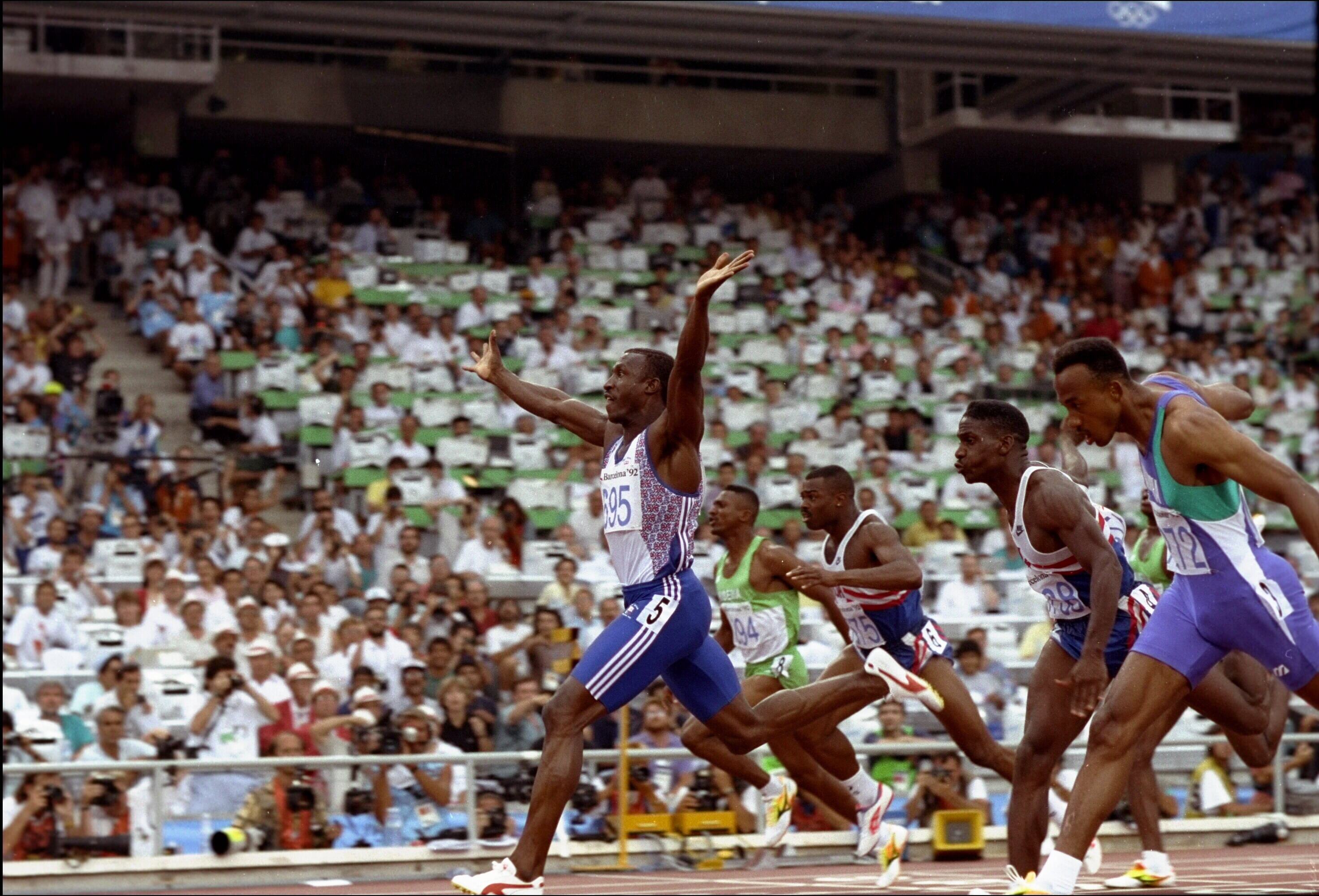 Jul 1992:  Sprinter Linford Christie of Great Britain raises his hands in celebration as he crosses the finish line ahead of the pack to capture the gold medal in the men's 100m final in the 1992 Summer Olympic Games held in Barcelona, Spain.  Linford Chr