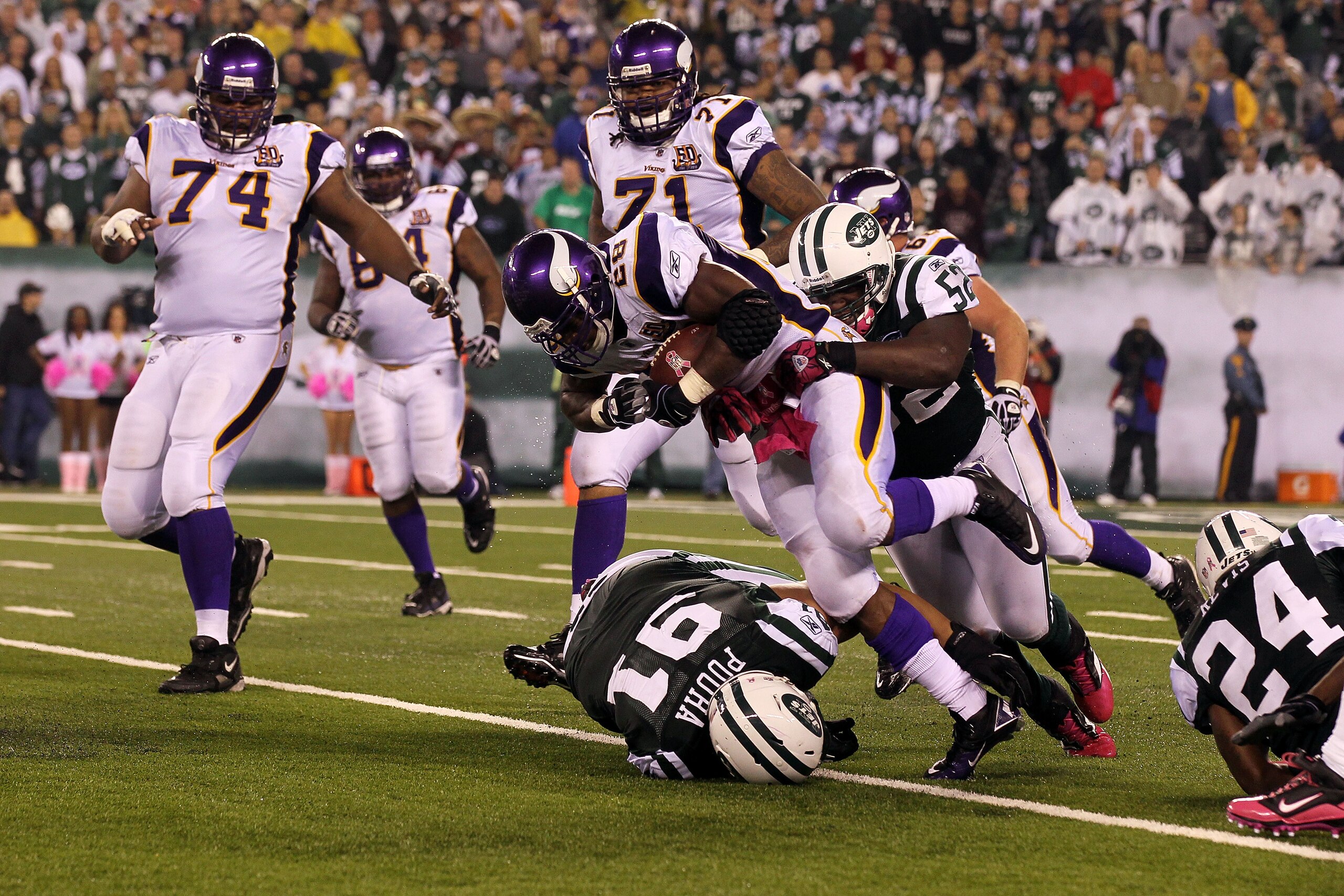 EAST RUTHERFORD, NJ - OCTOBER 11:  Adrian Peterson #28 of the Minnesota Vikings runs the ball against Sione Pouha #91 and David Harris #52 of the New York Jets at New Meadowlands Stadium on October 11, 2010 in East Rutherford, New Jersey. The Jets won 29-